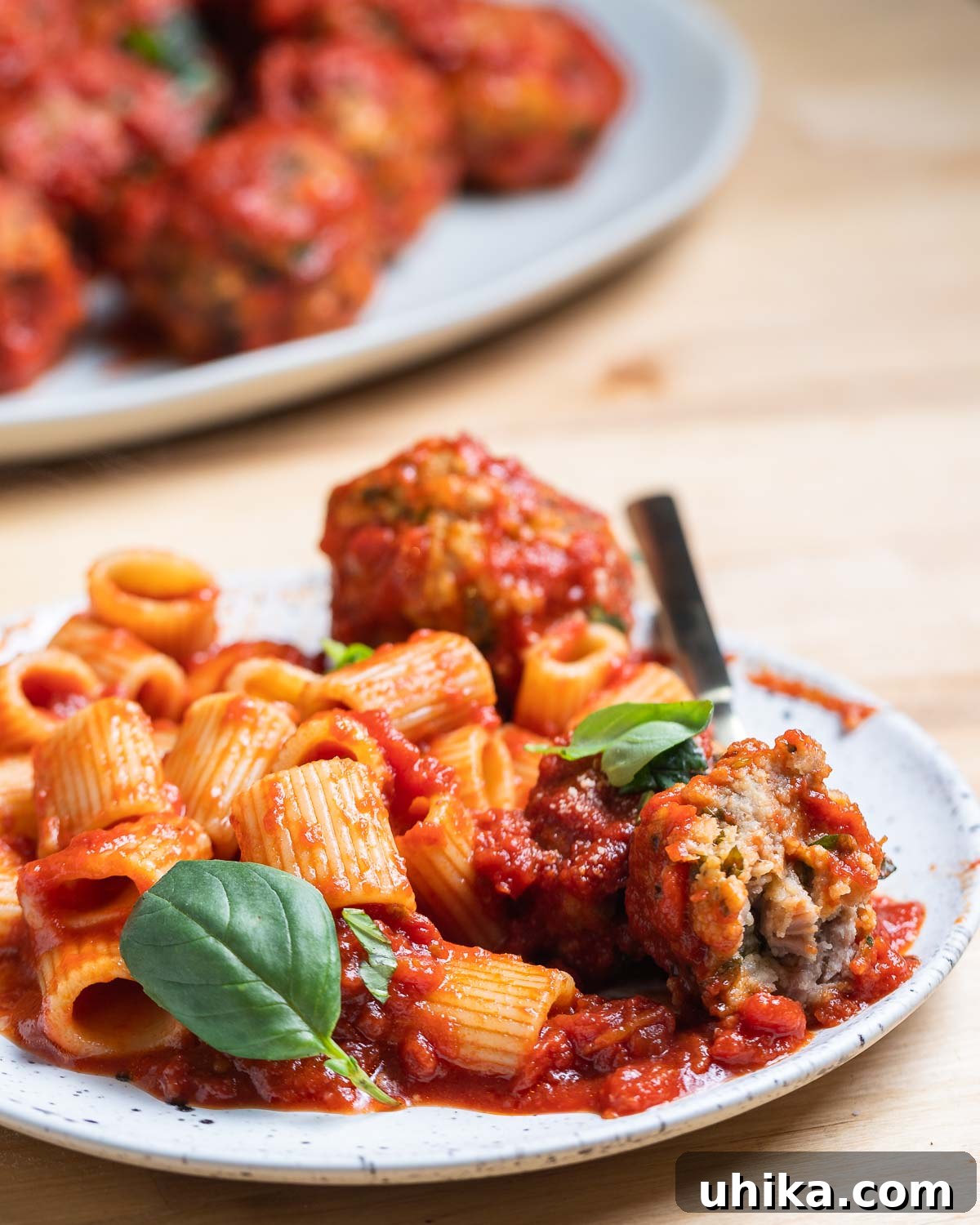 Flavorful Italian Sausage Meatballs 7 Cut in half sausage meatball with rigatoni and sauce on white plate.
