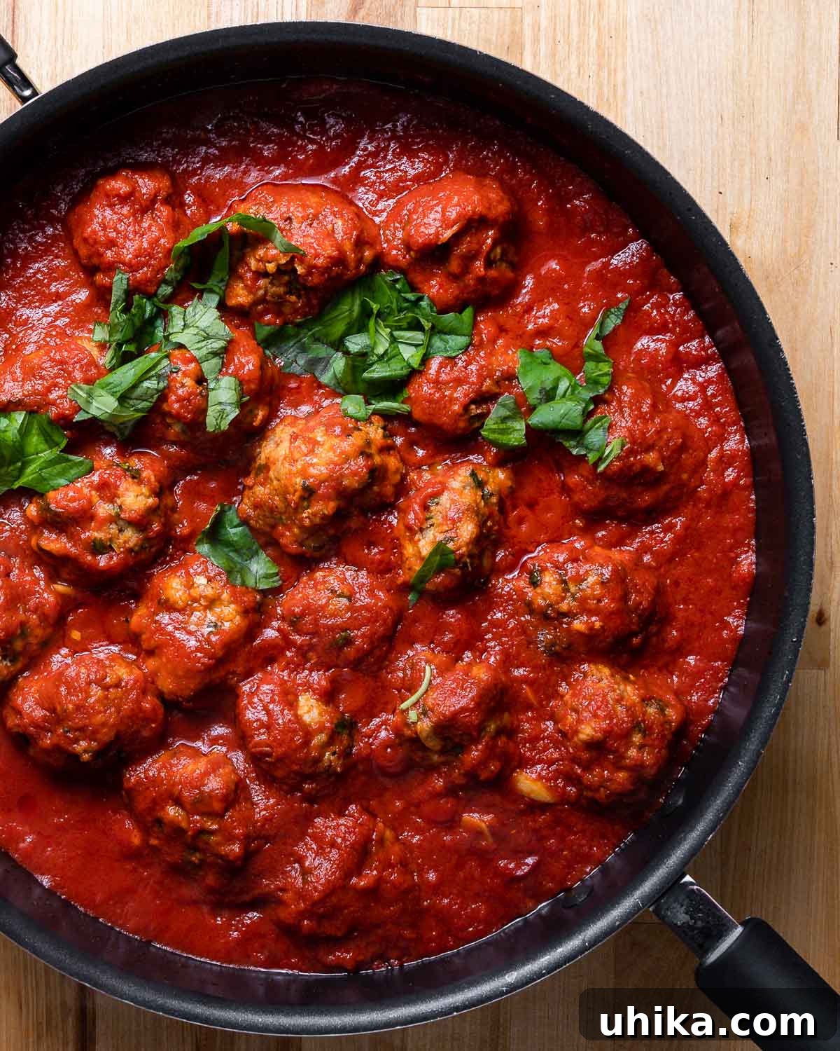 Flavorful Italian Sausage Meatballs 8 Sausage meatballs in large black pan with tomato sauce.