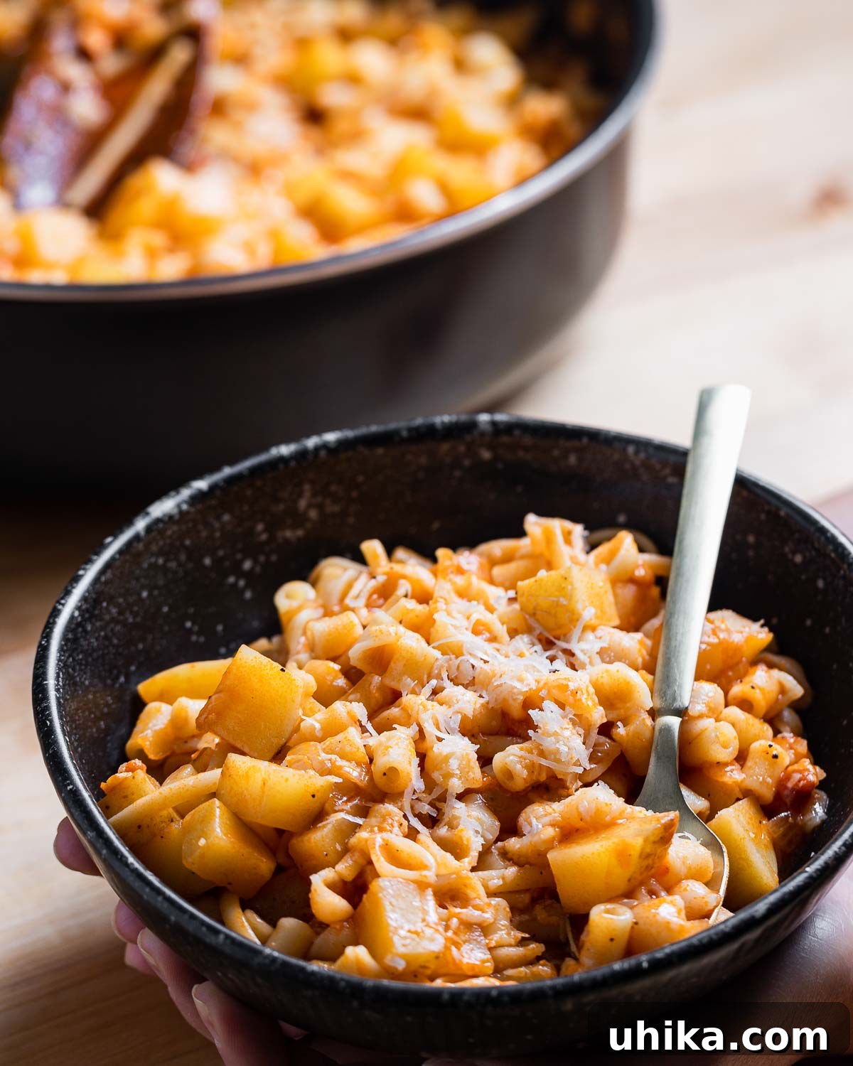 Pasta with Potatoes 9 A person's hands gently holding a rustic, inviting bowl filled with warm Pasta e Patate, symbolizing comfort and home-cooked goodness.