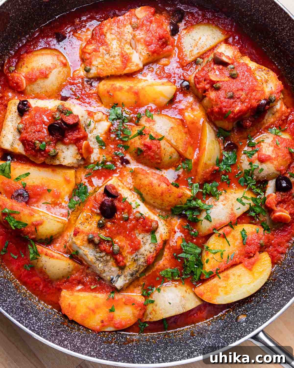 Naples' Signature Baccala 9 An overhead shot of a freshly baked Baccala alla Napoletana in a grey sauté pan, garnished with parsley.