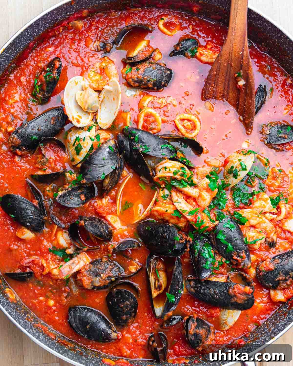 Hearty Italian Seafood Stew 2 Overhead shot of large pan with clams, mussels, calamari, and fish in tomato sauce.