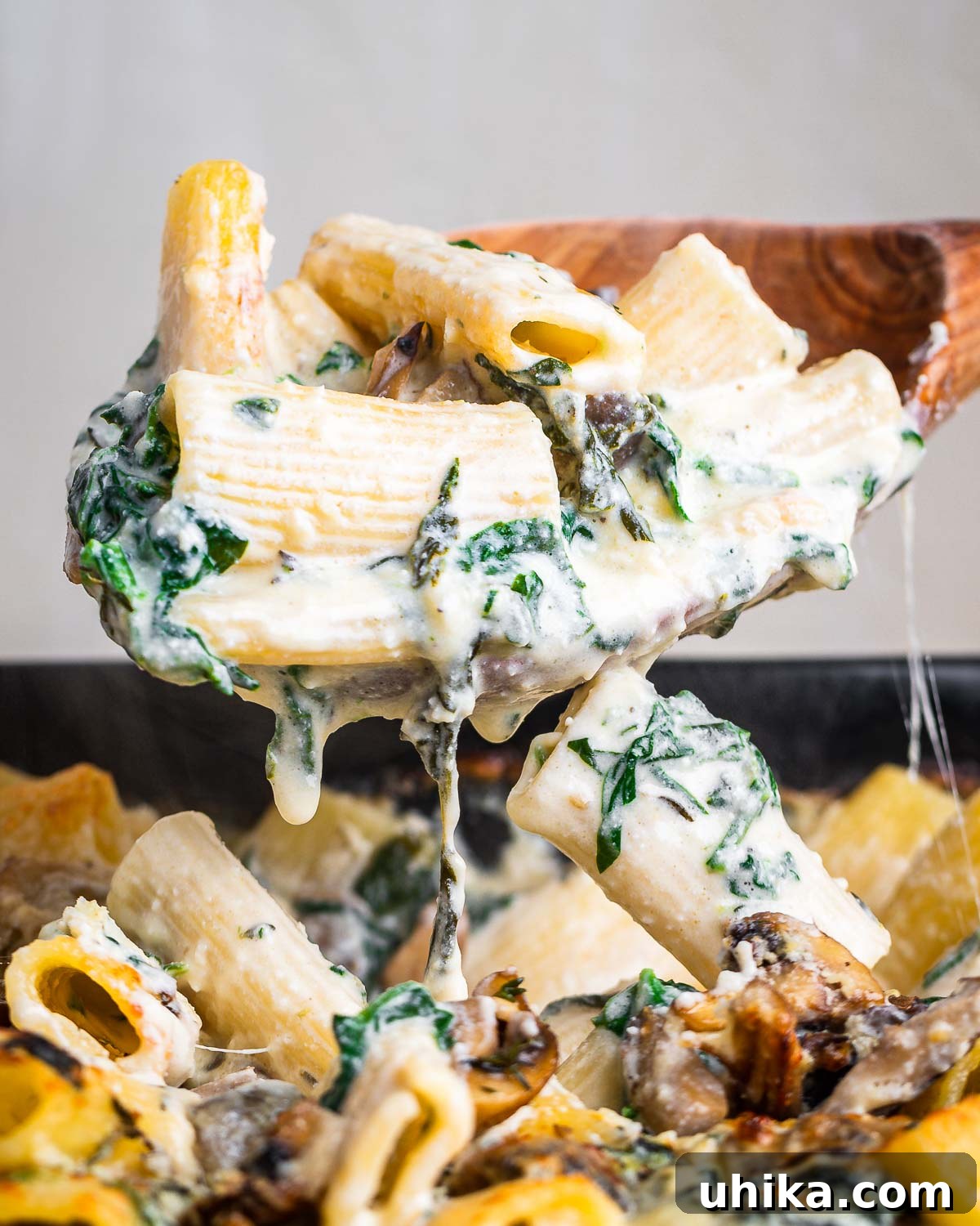Golden Mushroom Pasta Casserole 9 Large wooden spoon holding creamy mushroom pasta.