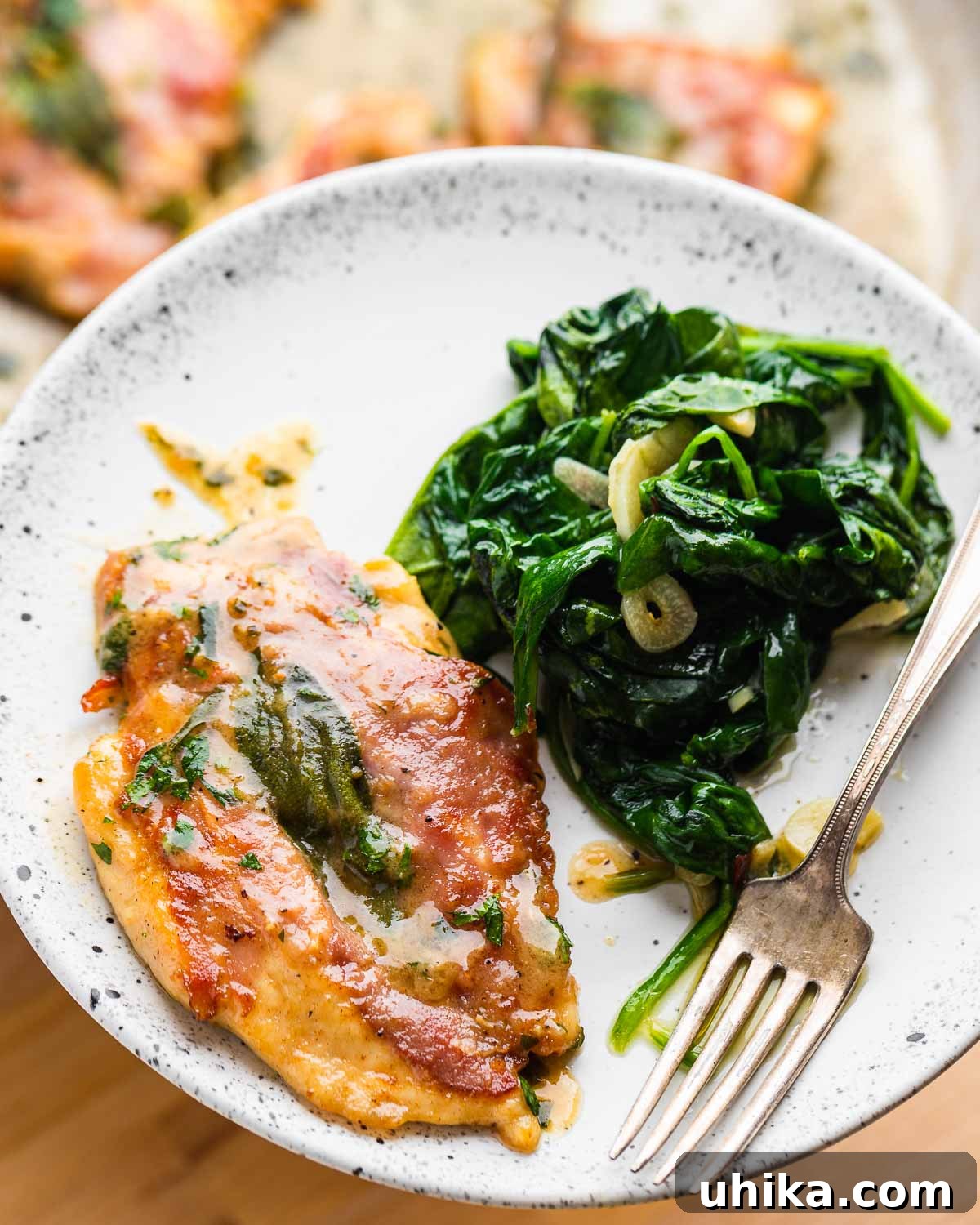 Prosciutto and Sage Chicken Saltimbocca 9 White plate held in hands with chicken saltimbocca and garlic spinach, ready to be enjoyed.