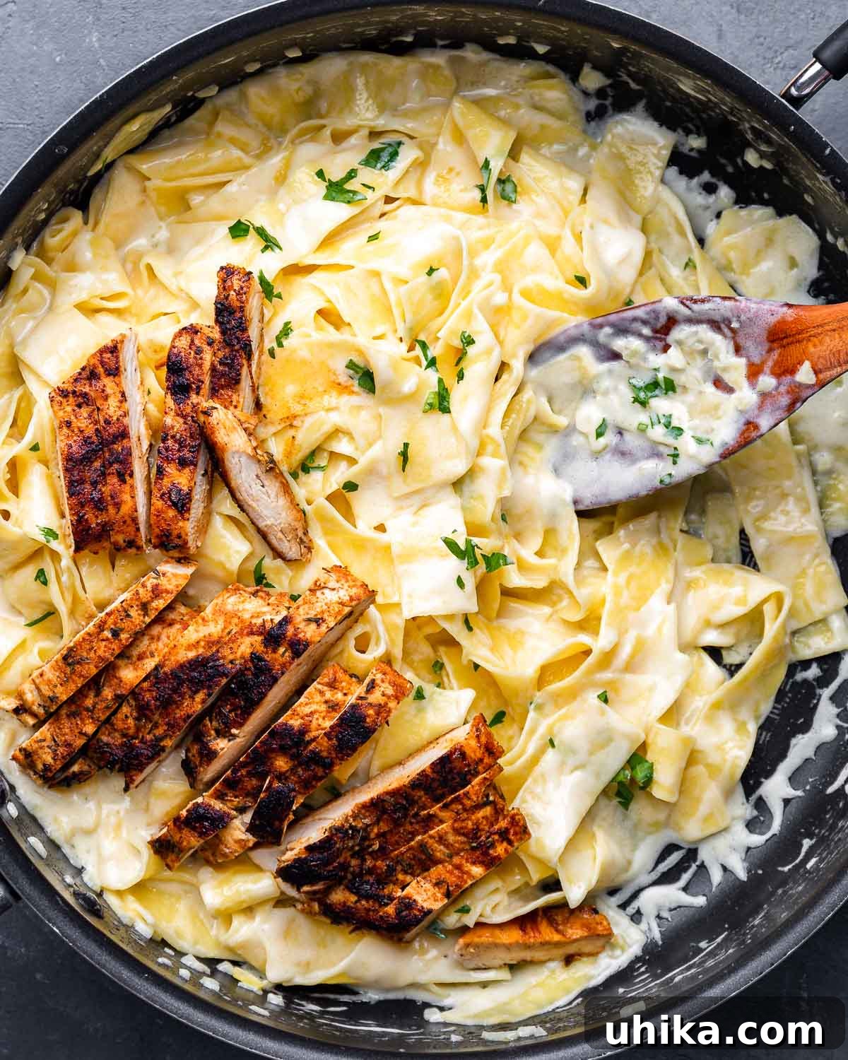 Decadent Chicken Alfredo Pasta 2 Overhead shot of creamy alfredo pasta with pieces of blackened chicken on top, garnished with fresh parsley.
