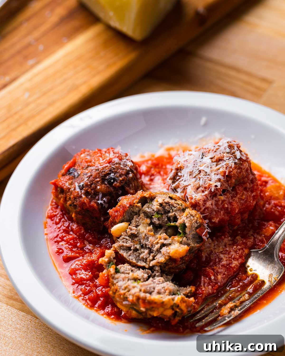 Mama's Sicilian Meatballs 7 Sicilian style meatball with sauce cut in half in white plate.