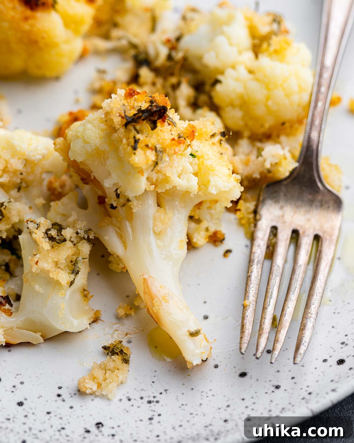 Golden Cauliflower Gratin 2 Roasted cauliflower with breadcrumbs and cheese in white plate, garnished with fresh parsley.