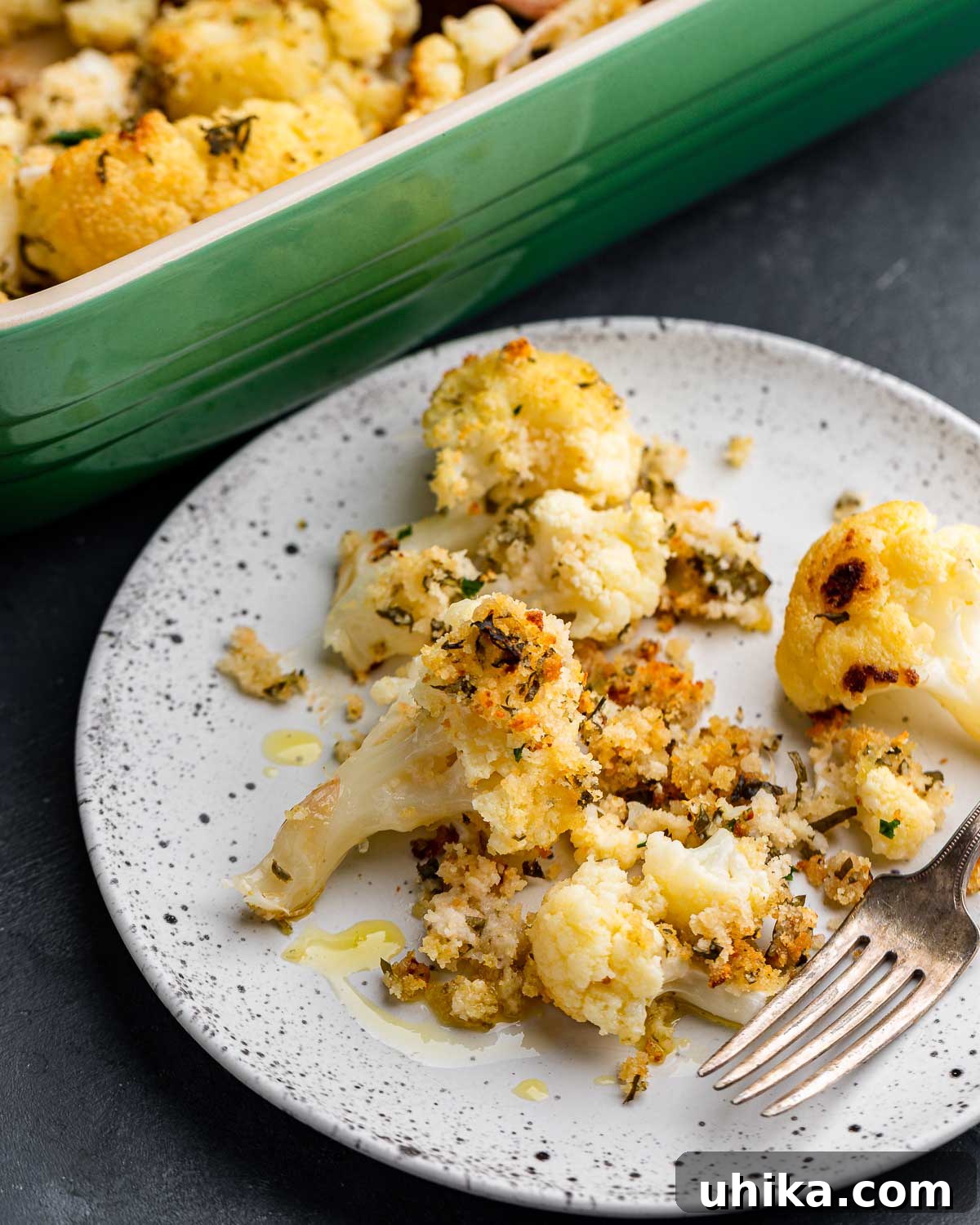 Golden Cauliflower Gratin 8 White plate and fork with a serving of baked cauliflower and breadcrumbs, ready to eat.