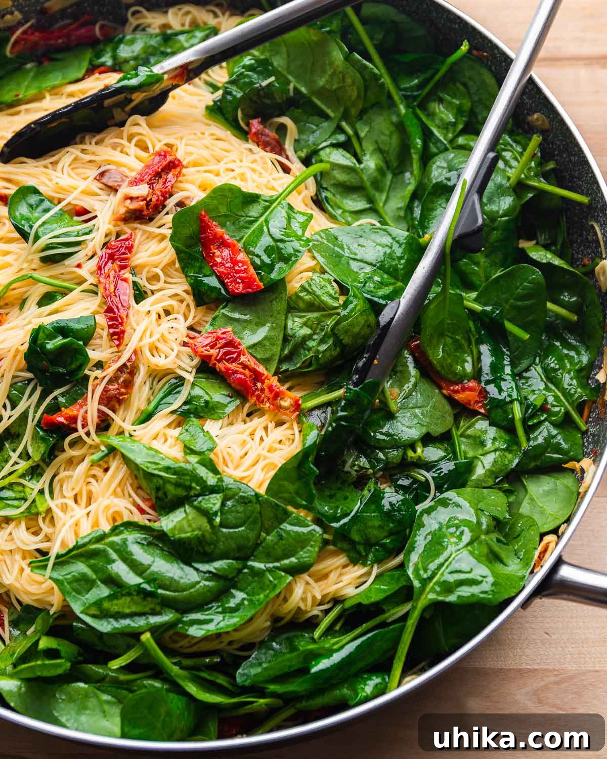 Sun-Drenched Spinach and Tomato Pasta 2 Large pan with spinach, sun dried tomato, and angel hair pasta, ready to serve