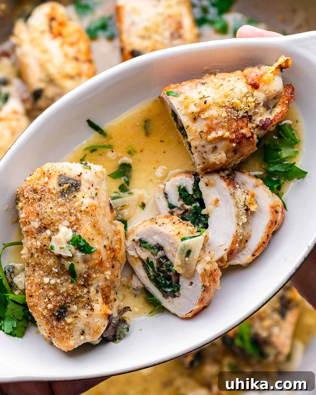 Stuffed Chicken Roulades 2 Hands holding small plate with sliced chicken involtini, showcasing the delicious filling.