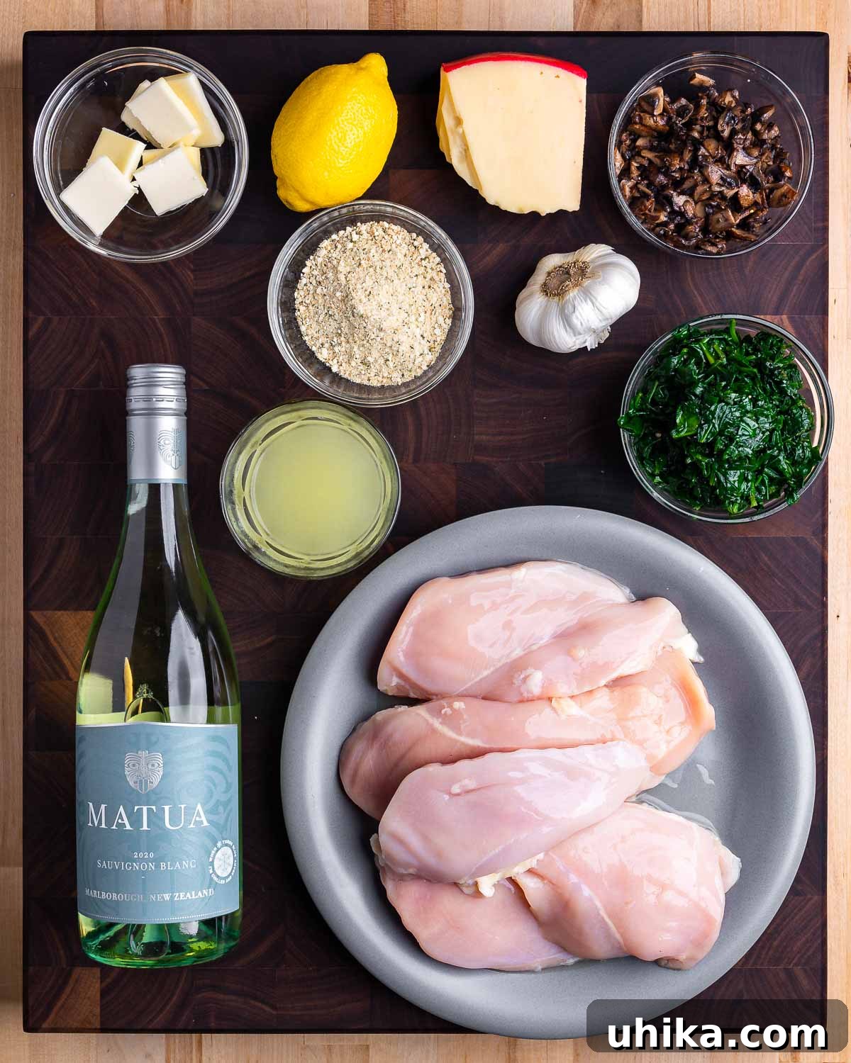 Stuffed Chicken Roulades 3 Ingredients shown: butter, lemon, breadcrumbs, cheese, garlic, spinach, mushrooms, chicken stock, white wine, and chicken breasts, laid out for chicken involtini preparation.