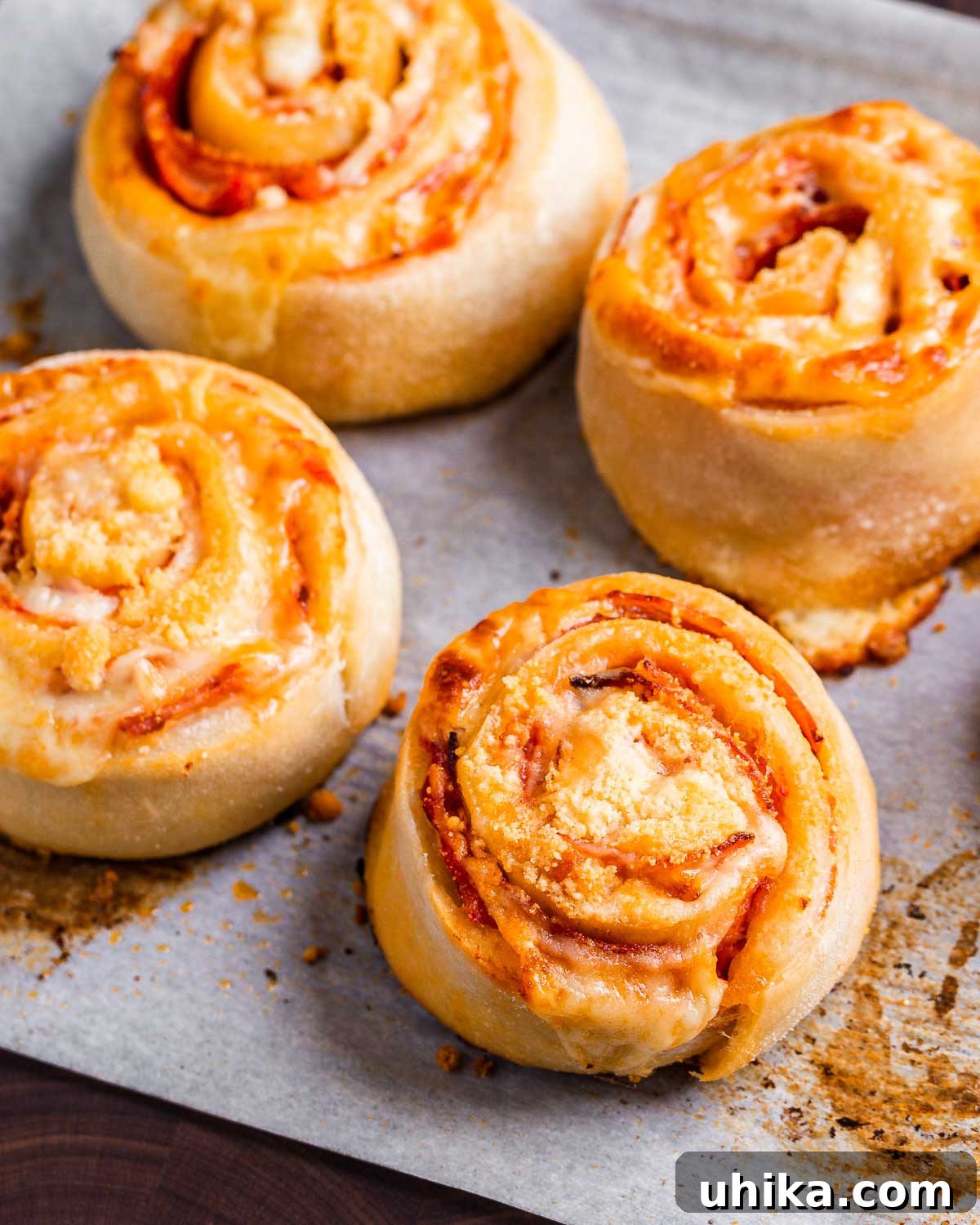 Cooked pepperoni pinwheels on parchment paper, ready to serve.