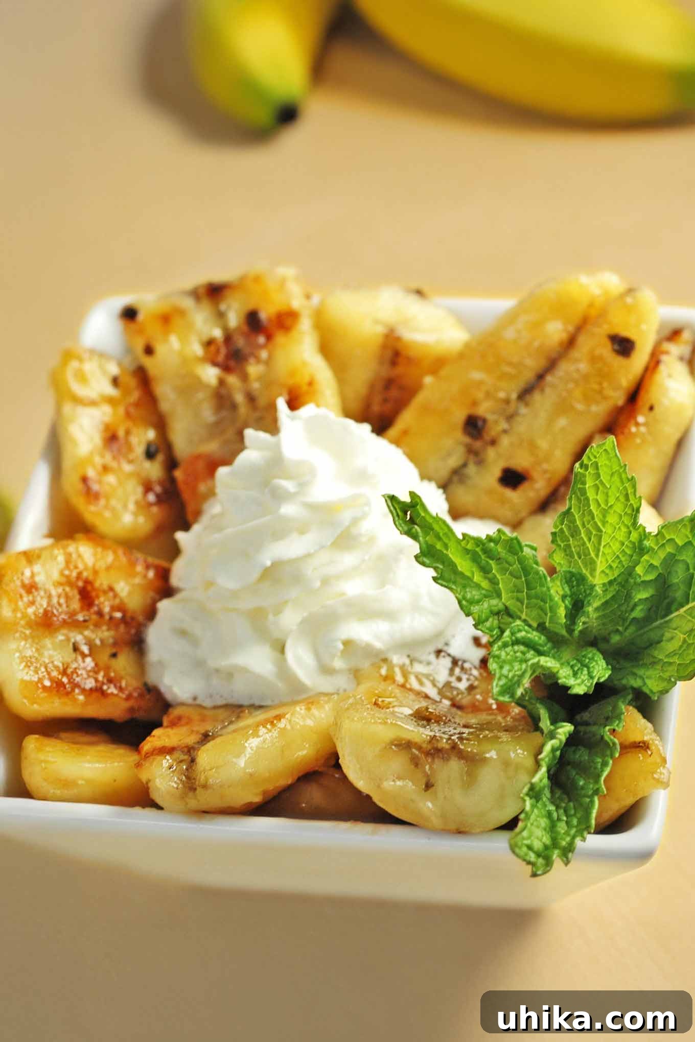 Tropical Gold 2 Bowl of Caribbean bananas caramelized in butter, brown sugar, rum, and lime, topped with whipped cream and garnished with fresh mint.