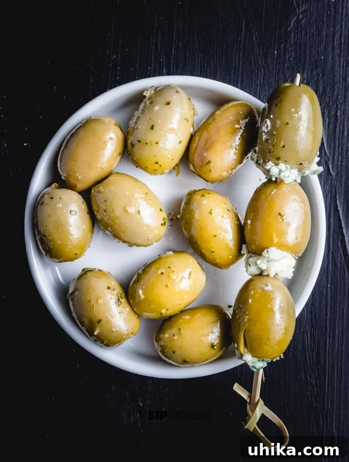 Blue Cheese Olive Martini - sipandfeast.com #martini #cocktails #bluecheese #olives A small dish brimming with plump, green olives, each carefully stuffed with creamy blue cheese, ready to garnish a gourmet martini.
