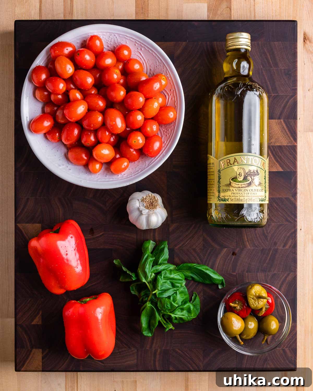 Zesty Cherry Pepper Preserve 3 A vibrant array of fresh ingredients for cherry pepper spread: cherry tomatoes, olive oil, red bell peppers, garlic, basil, and pickled cherry peppers, laid out on a clean surface.