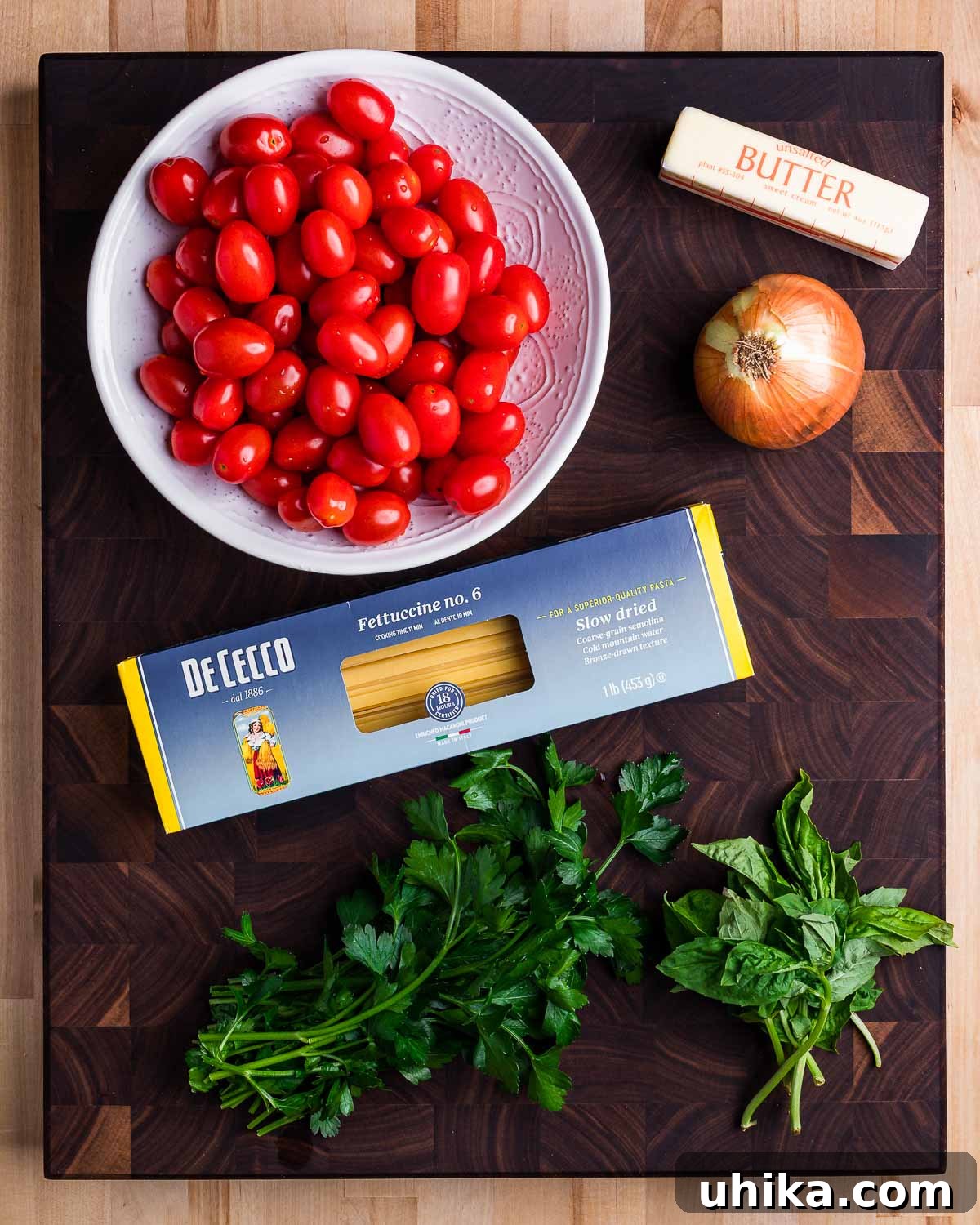 Blushing Cherry Tomato Butter Fettuccine 3 Ingredients laid out for fettuccine with cherry tomato butter sauce, including cherry tomatoes, butter, onion, fettuccine, parsley, and basil.