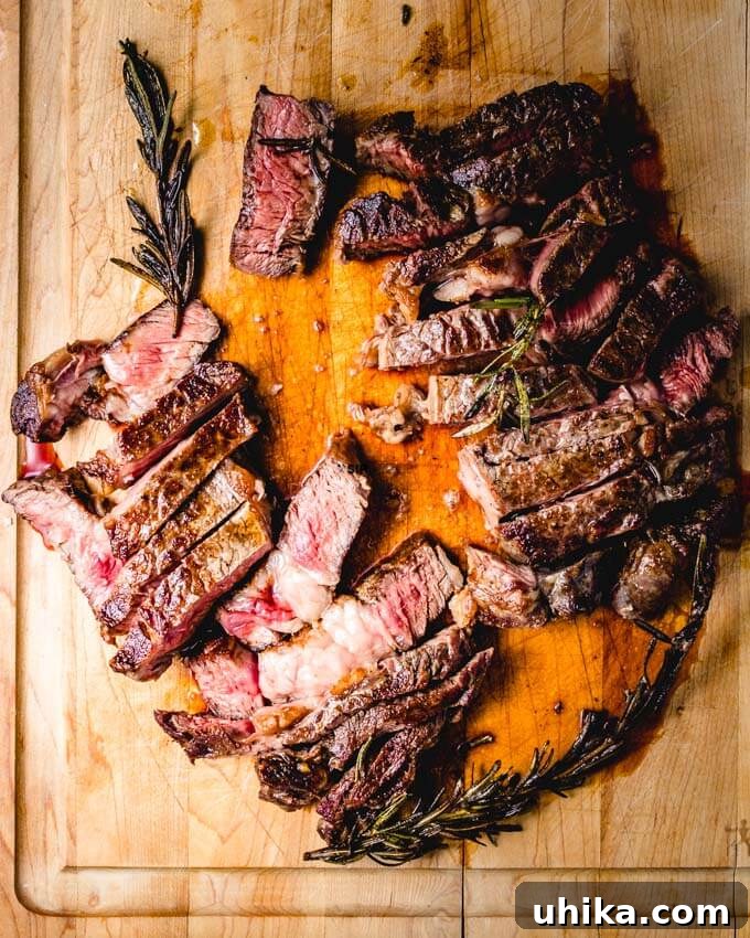 Reverse Seared Ribeye Steaks - sipandfeast.com #reversesear #ribeye #steak #dinner Rosemary ribeye sliced on cutting board.