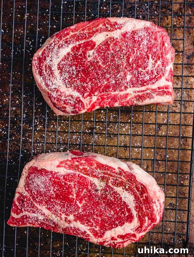 Reverse Seared Ribeye Steaks - sipandfeast.com #reversesear #ribeye #steak #dinner Salt and pepper on ribeyes on wire rack.