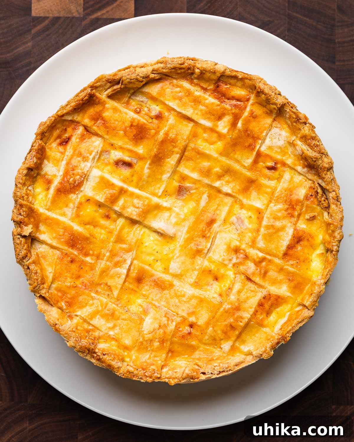 Rustic Italian Easter Feast Pie 10 Cooked Easter pie (pizzagaina) in white plate on brown cutting board.