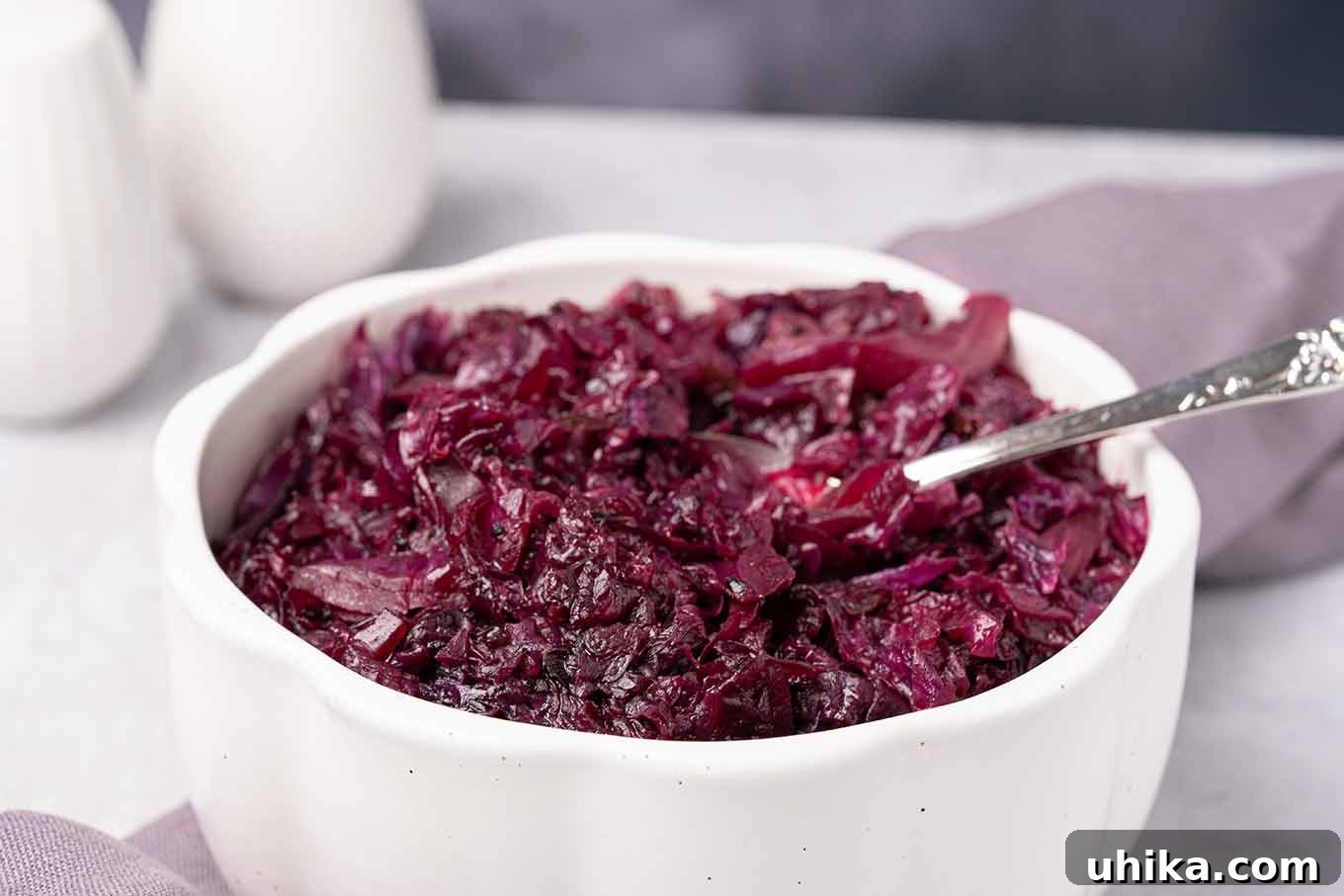 Sweet and Tangy Braised Red Cabbage 3 A serving bowl of red cabbage that was braised in apple cider and currant jelly with a serving spoon in it.