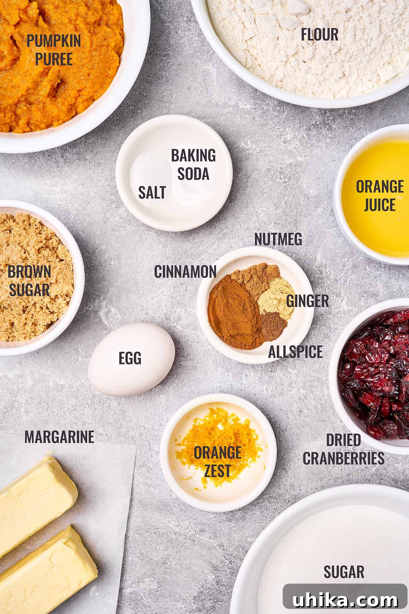 Spiced Pumpkin Cranberry Cookie Delights 3 A labeled, overhead view of the ingredients needed to make pumpkin cranberry cookies including pumpkin puree, orange juice, dried cranberries, orange zest, and more.