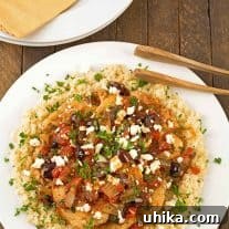 A dinner plate with boneless chicken breasts, topped with a light sauce of tomatoes, Kalamata olives and feta cheese served over a bed of riced cauliflower.
