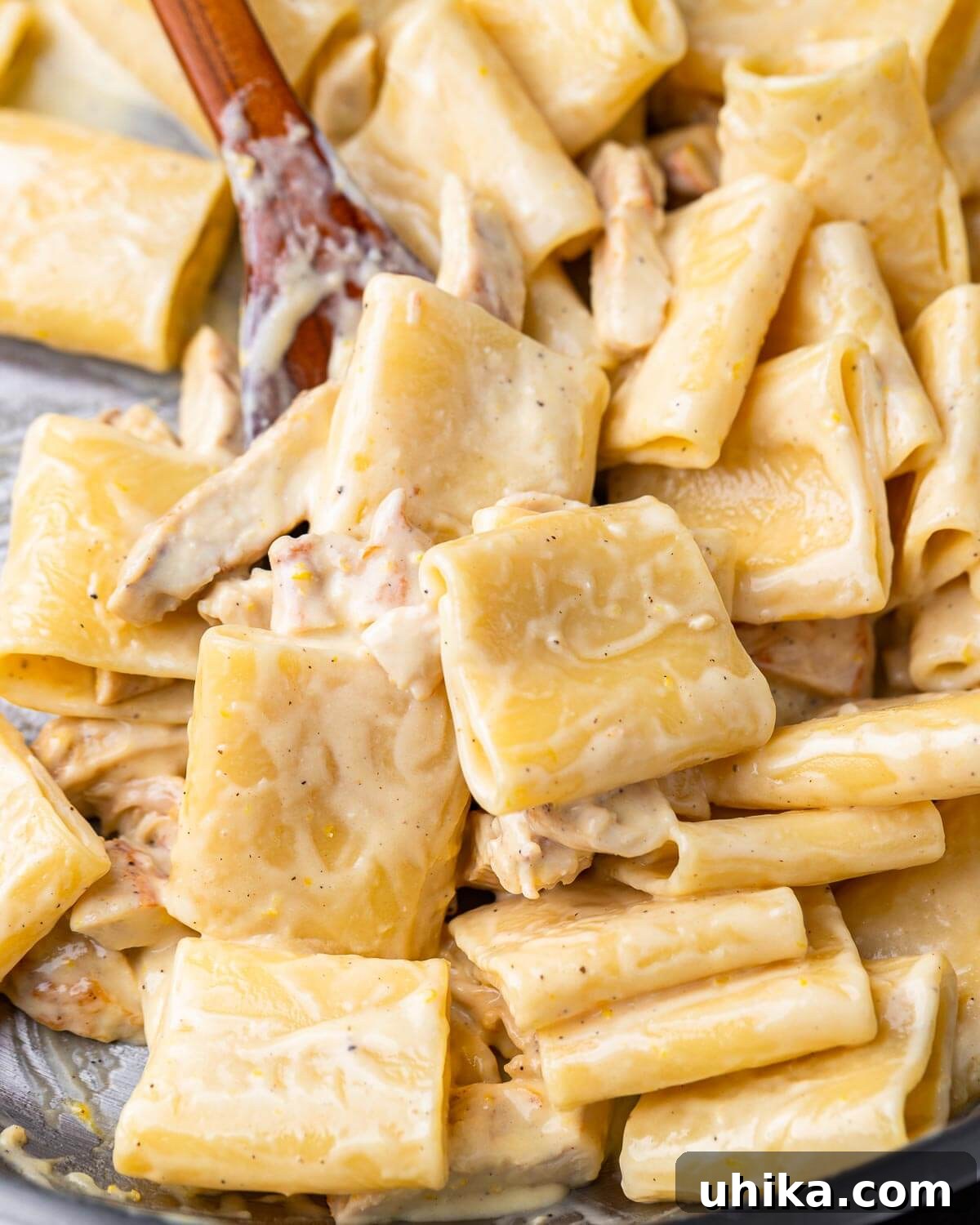 Luscious Lemon Chicken Pasta 6 Creamy lemon chicken paccheri in pan with wooden spoon.