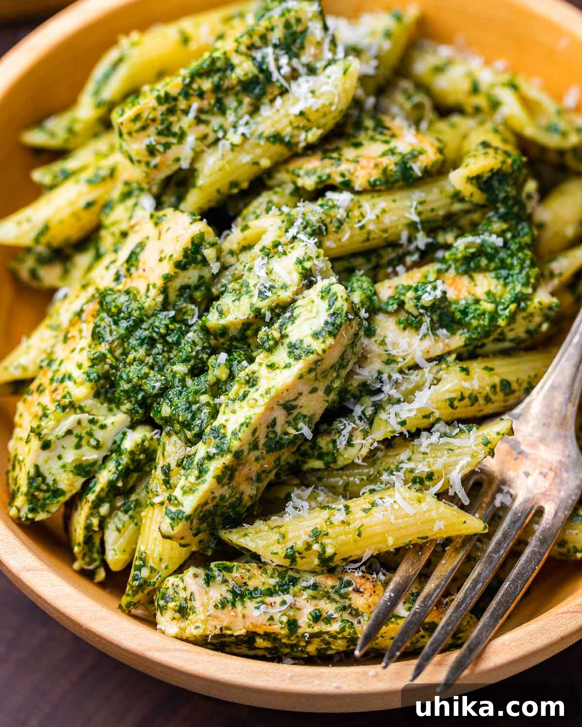 Basil Pesto Chicken Pasta 2 Chicken pesto pasta salad in wooden bowl. A rustic wooden bowl filled with vibrant chicken pesto pasta salad, garnished with fresh basil leaves, ready to be served.
