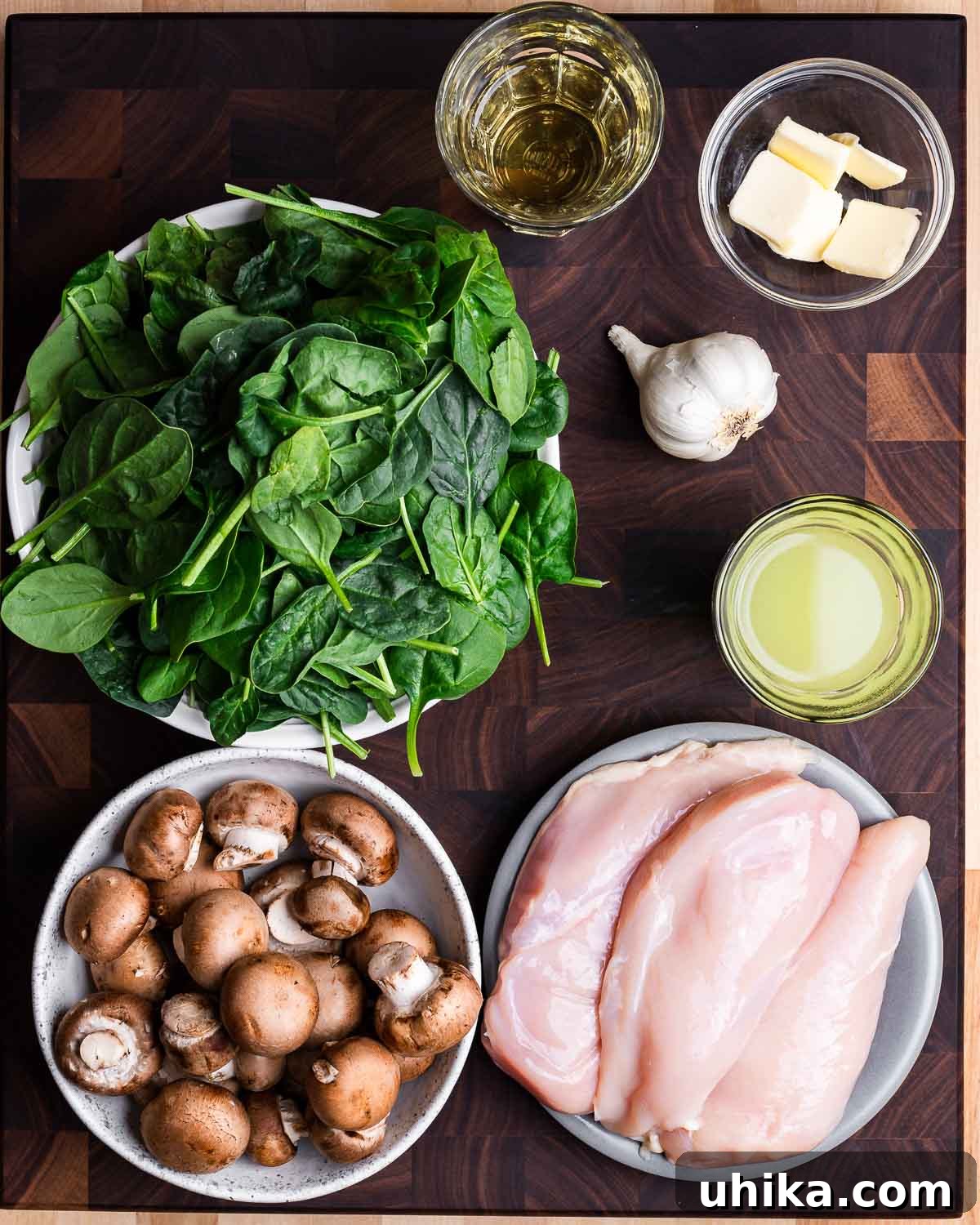 Chicken with Spinach and Mushroom Medley 3 All ingredients for spinach mushroom chicken laid out: white wine, butter, fresh spinach, garlic, chicken stock, cremini mushrooms, and raw chicken breasts.