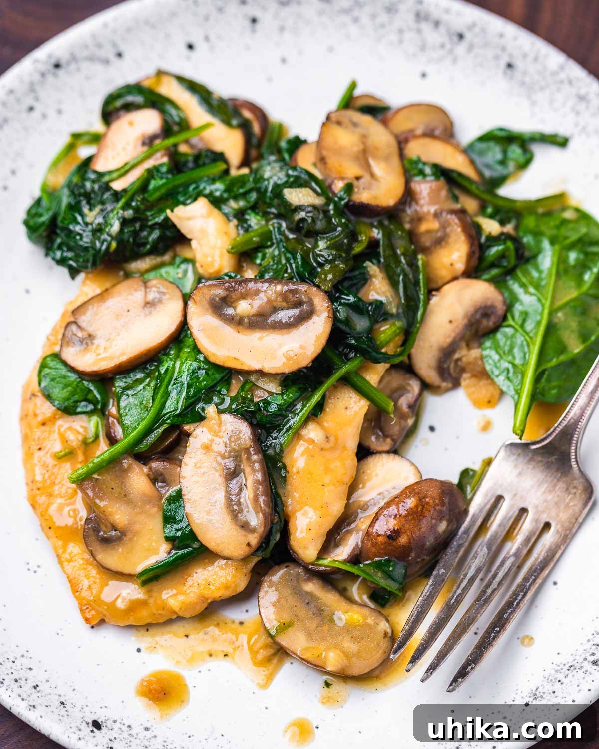 Chicken with Spinach and Mushroom Medley 7 Spinach mushroom chicken served on a white plate with sauce and fresh parsley garnish.