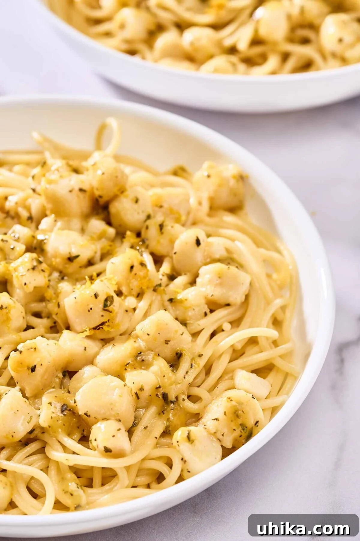Sun-Kissed Sicilian Bay Scallop Pasta 8 A close view of a serving of spaghetti and scallops tossed with a vibrant citrus sauce, showing delicate bits of fresh herbs and orange zest clinging to the pasta.