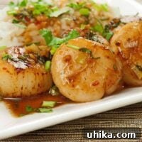 Close-up of perfectly seared Thai Sweet Chili and Orange Scallops with fresh herbs