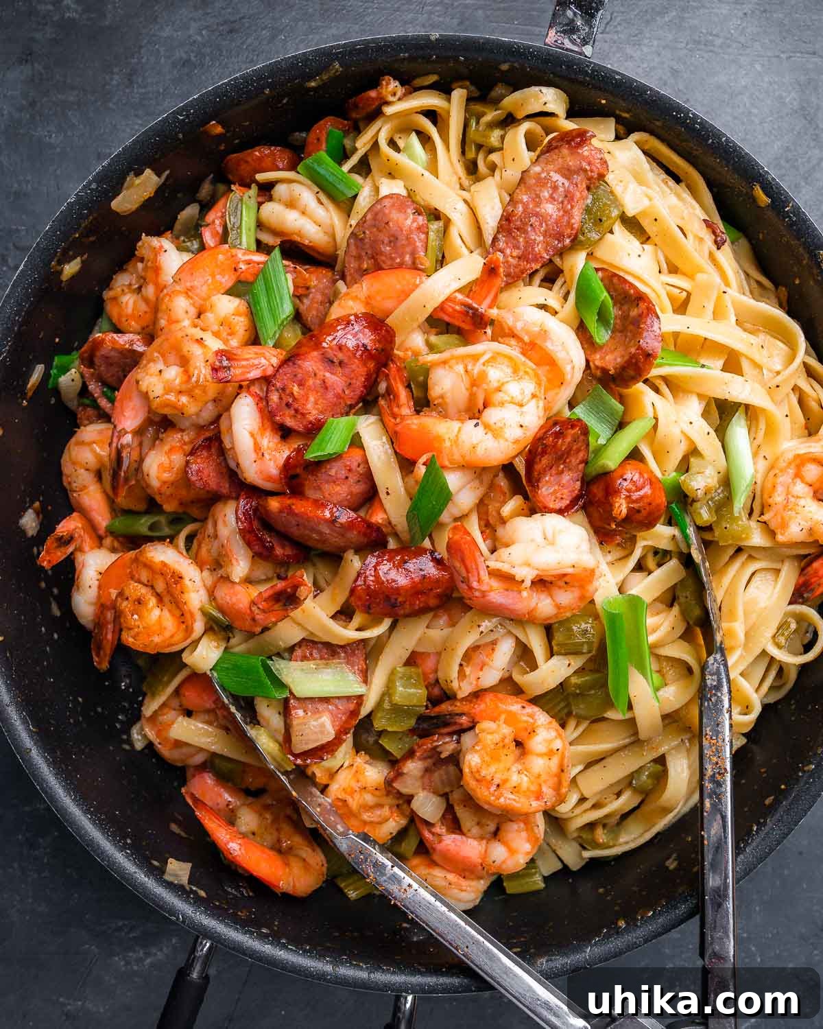 Bayou Shrimp and Sausage Pasta 2 Overhead shot of Cajun shrimp and sausage pasta in large pan with tongs, highlighting the vibrant colors and hearty ingredients.