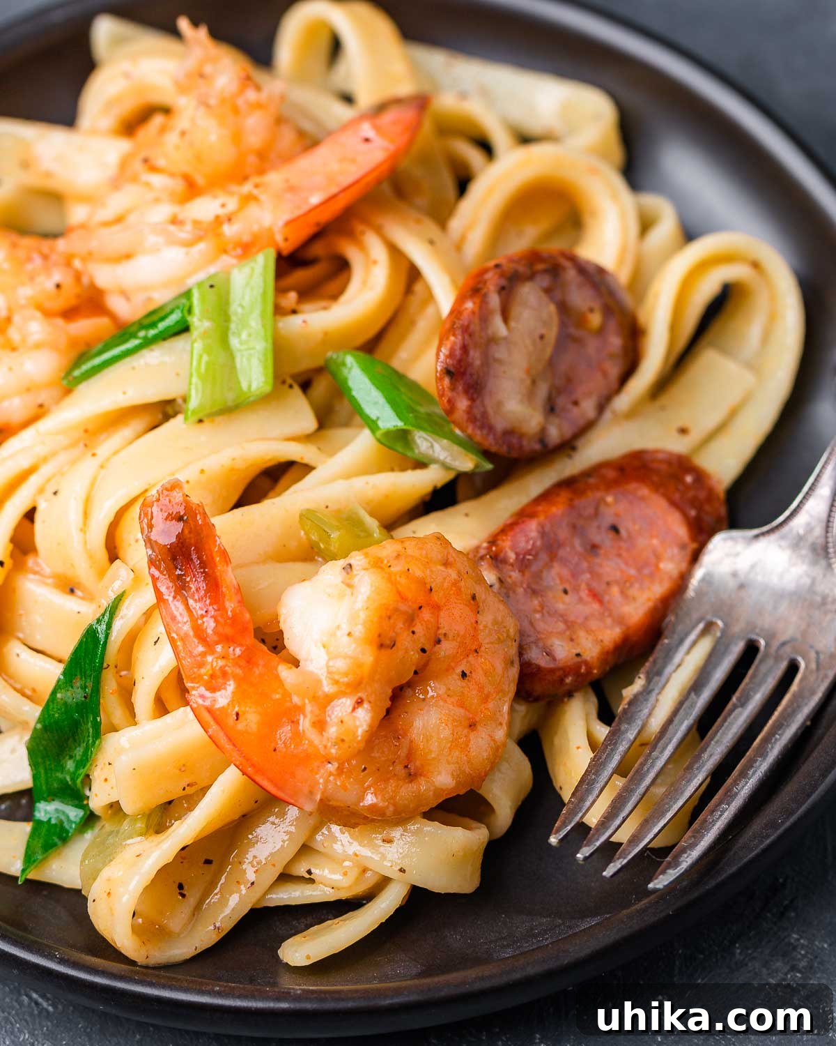 Bayou Shrimp and Sausage Pasta 7 Cajun shrimp and sausage pasta in small plate with fork, ready to be enjoyed.