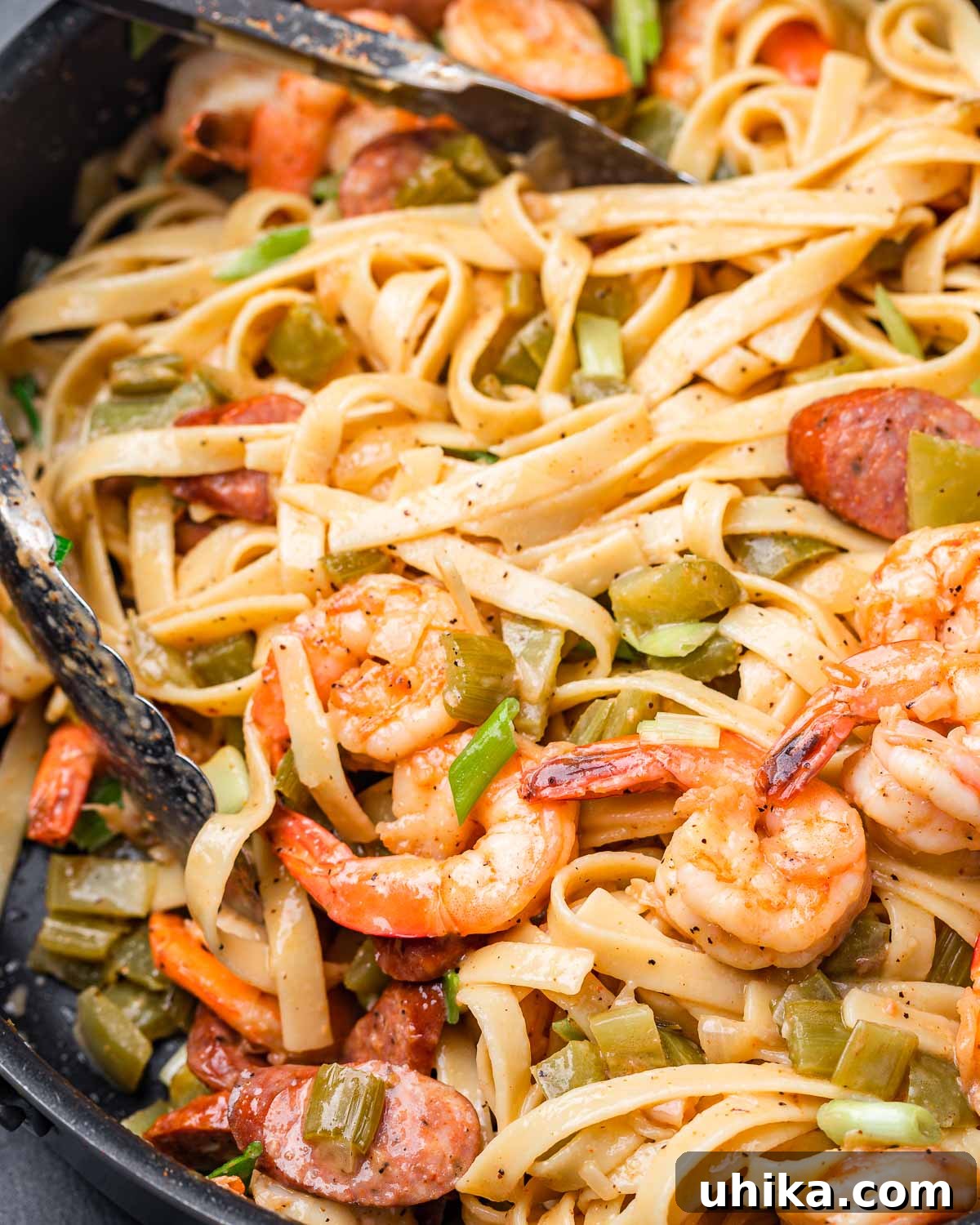 Bayou Shrimp and Sausage Pasta 8 Cajun shrimp and sausage pasta in large pan with tongs, showcasing the finished dish ready to be served.