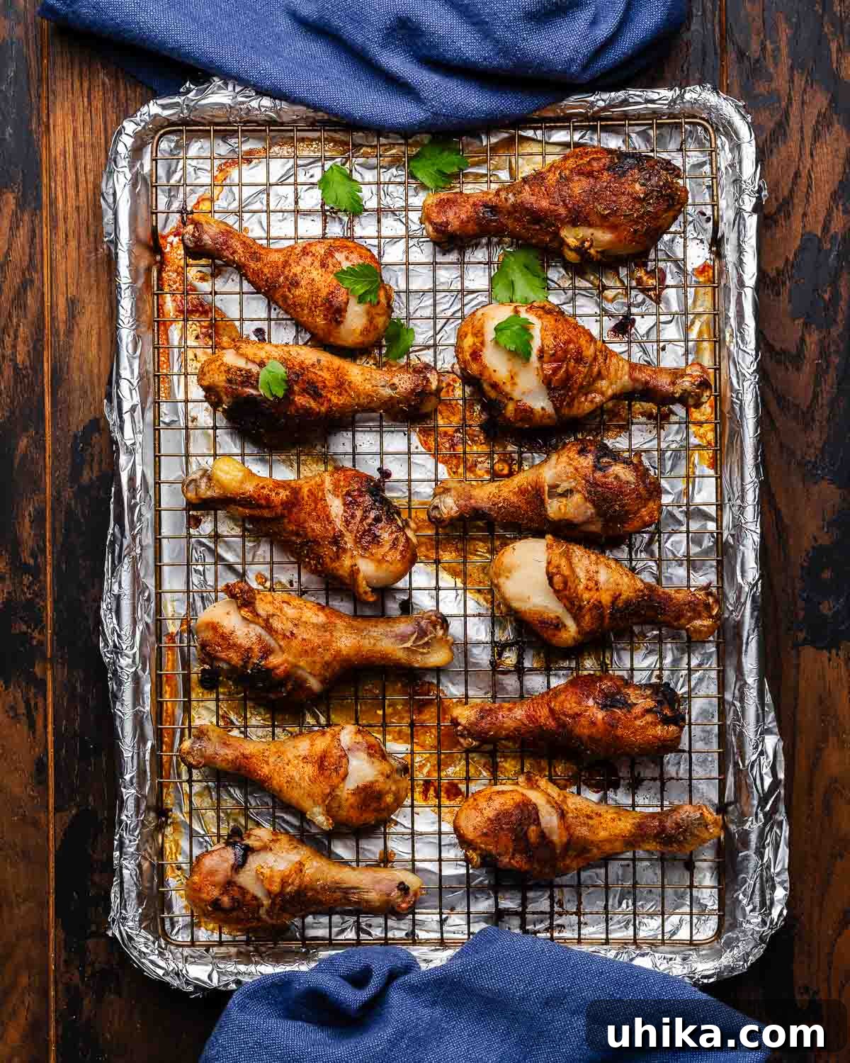 Effortless Cajun Roasted Drumsticks 7 Crispy Baked Cajun chicken legs arranged on a wire rack with foil underneath.