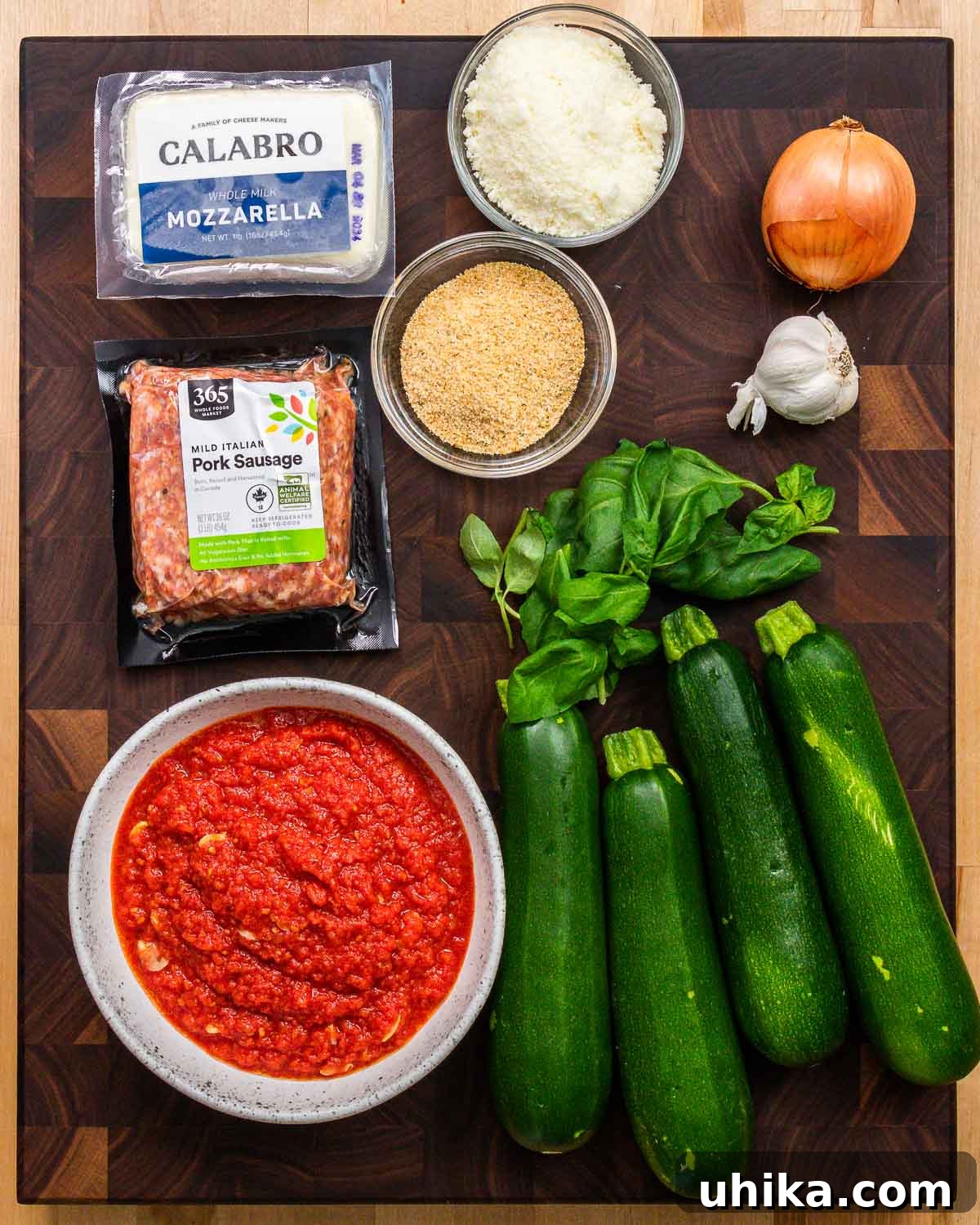 Sausage Stuffed Zucchini Bake 3 Ingredients shown: mozzarella, Pecorino, breadcrumbs, onion, garlic, bulk sausage, basil, zucchini, and marinara sauce.