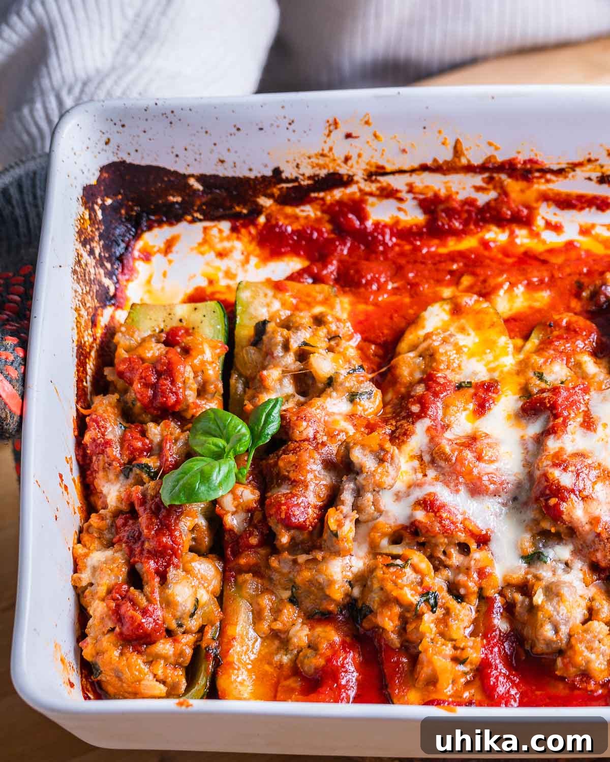 Sausage Stuffed Zucchini Bake 9 Person holding baking dish with sausage stuffed zucchini boats.