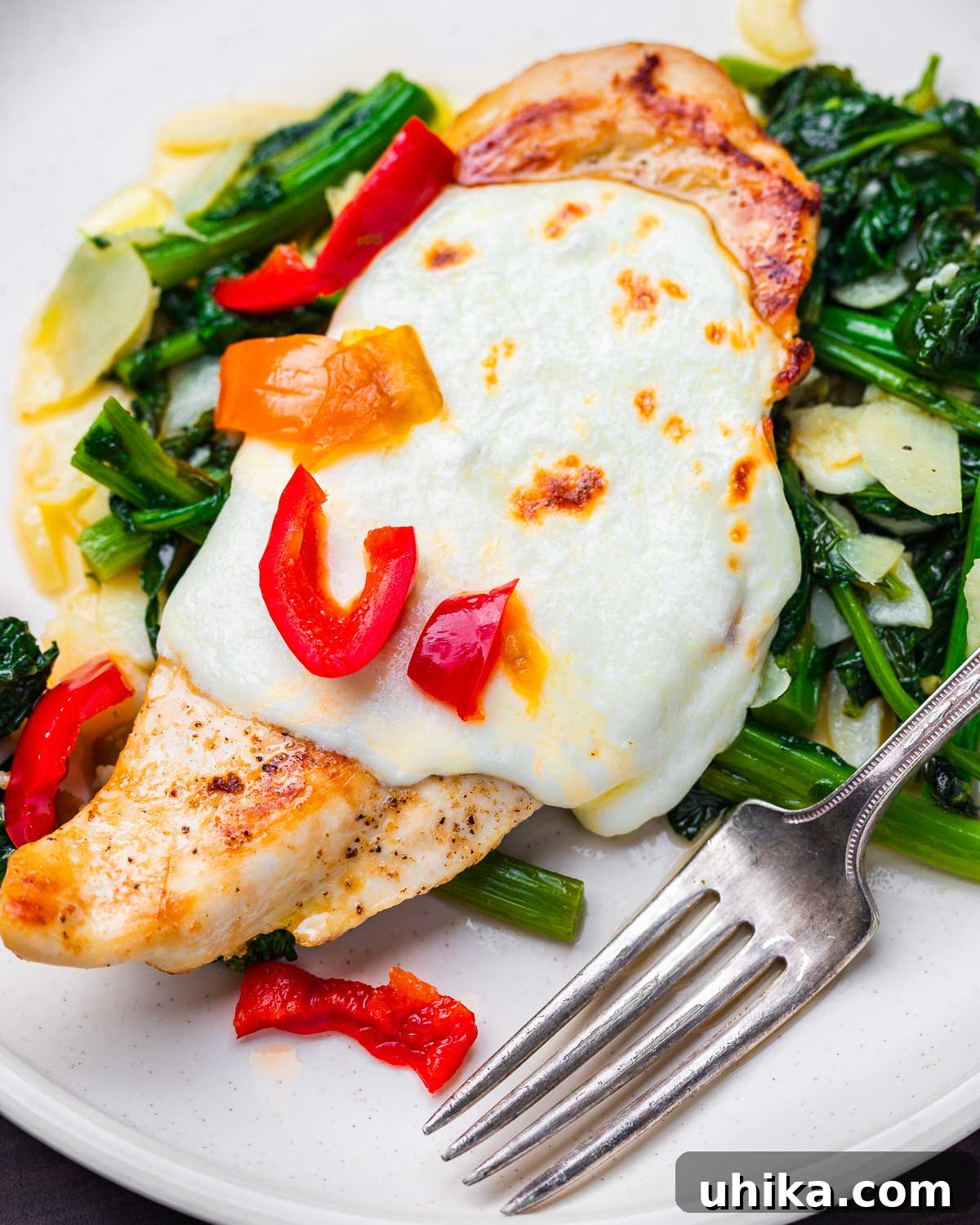 Pan-Seared Chicken with Garlicky Broccoli Rabe 2 Chicken and broccoli rabe with mozzarella and cherry peppers in white plate.