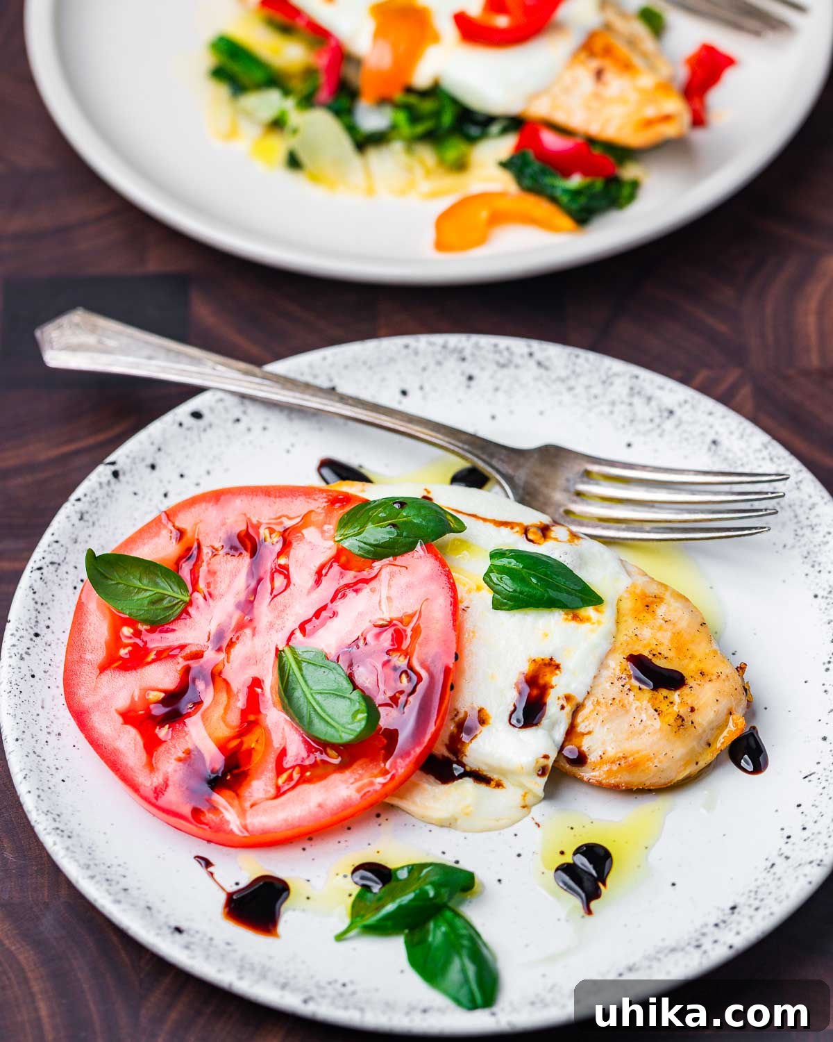 Pan-Seared Chicken with Garlicky Broccoli Rabe 7 Chicken with mozzarella, tomato, basil, and balsamic glaze in white plate.