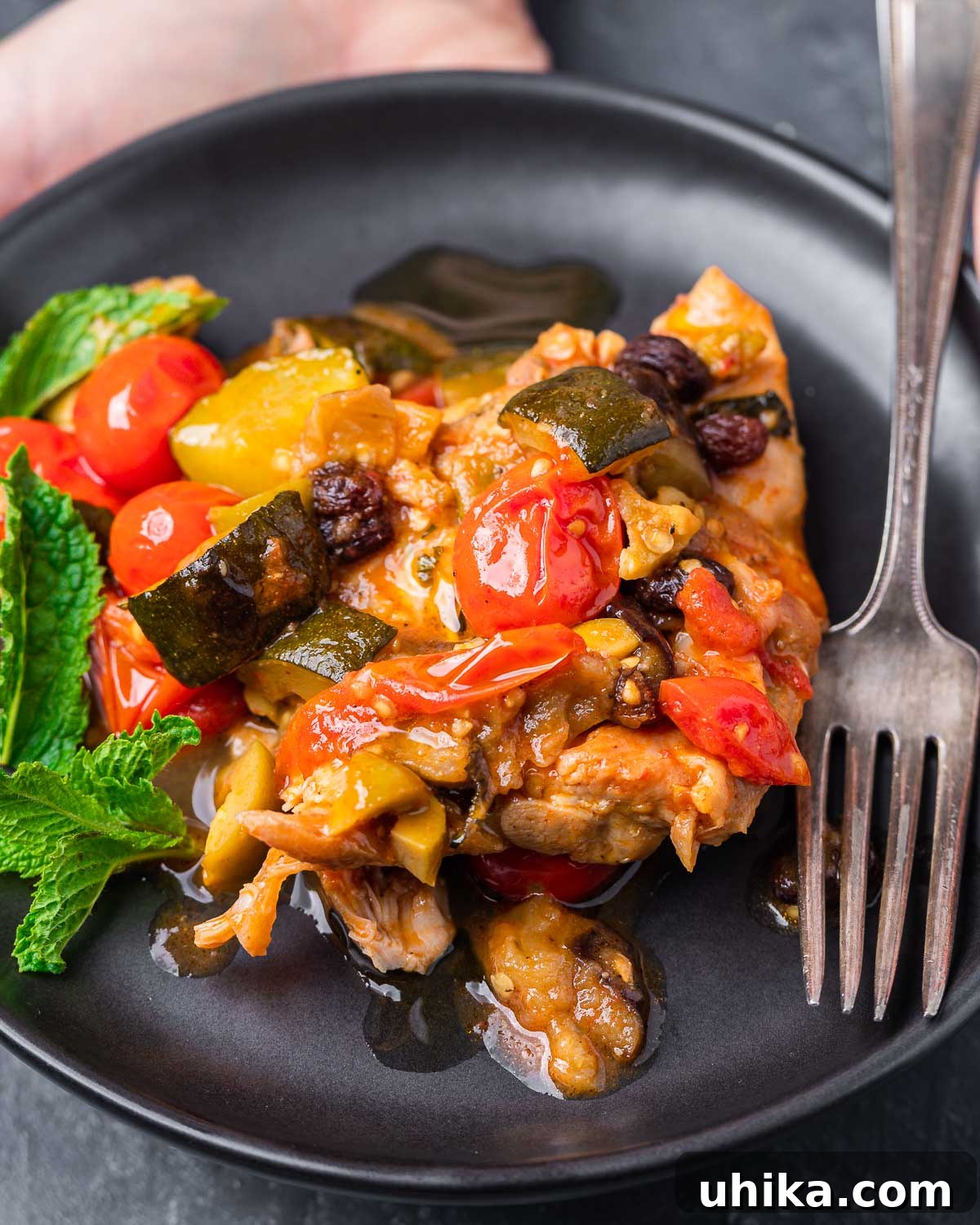 Sicilian Agrodolce Chicken 2 A serving of Chicken Agrodolce in a black plate, showcasing tender chicken, roasted vegetables, and a rich sauce.