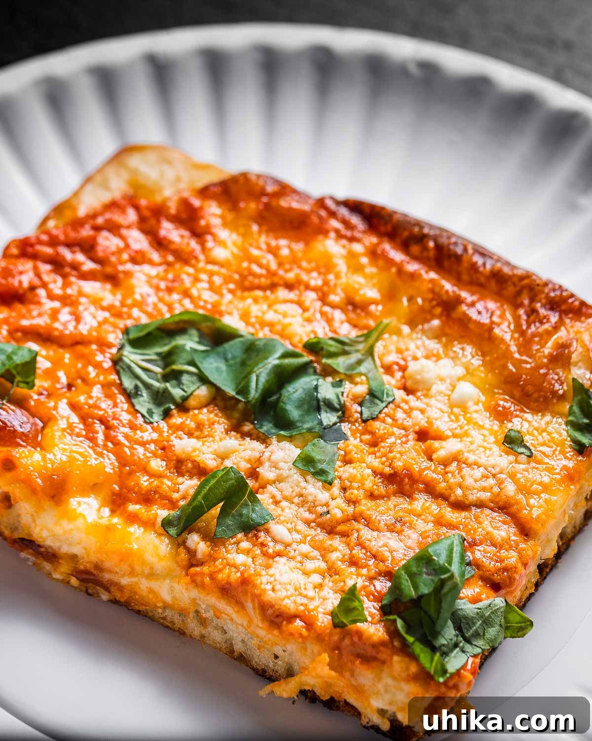 Rose Vodka Pizza 2 A delectable slice of vodka sauce pizza presented on a pristine white paper plate, highlighting its golden crust and vibrant toppings.