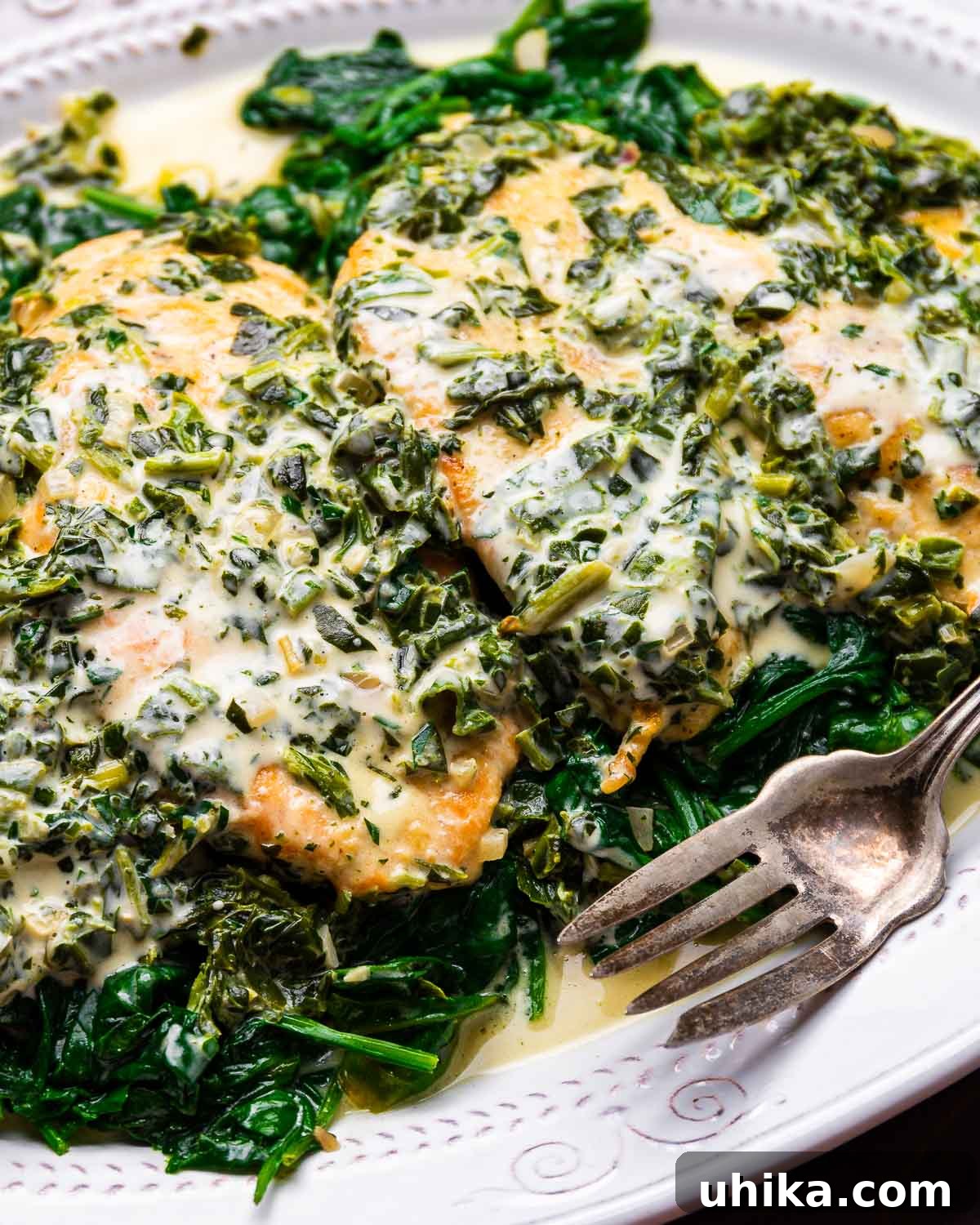 Creamy Tuscan Chicken 2 Beautifully plated Chicken Florentine on a bed of spinach in a white platter.