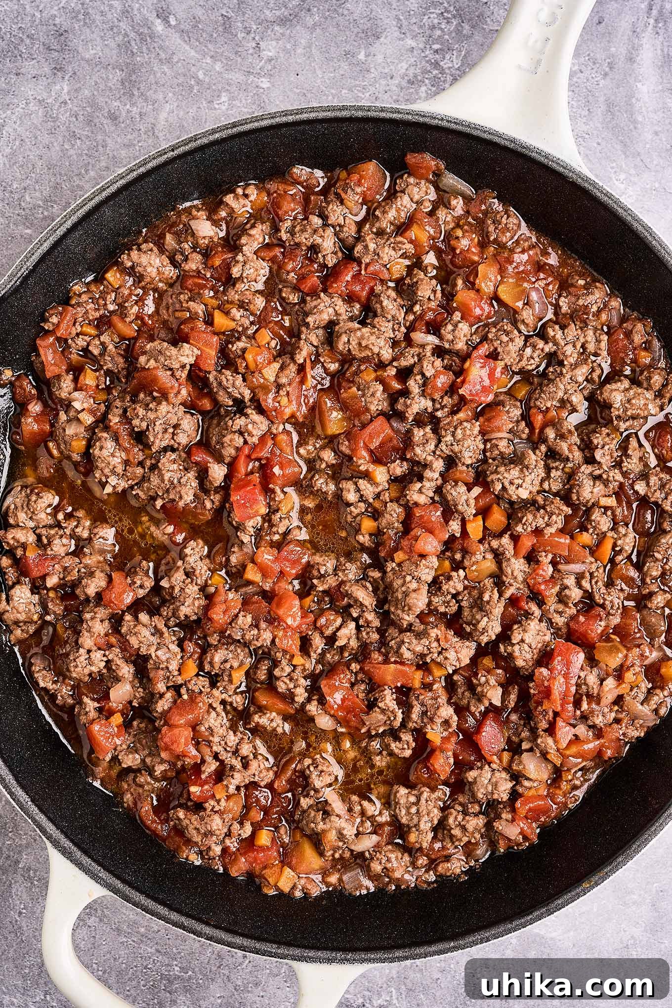 Effortless Ground Lamb Ragu 6 A cast iron pan filled with sautéed ground lamb, chopped carrots, and diced tomatoes, ready for the addition of sliced leeks.