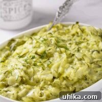 An oval serving bowl of Hungarian summer squash with dill; shredded zucchini with a flavorful sauce of sour cream, vinegar, and fresh dill.