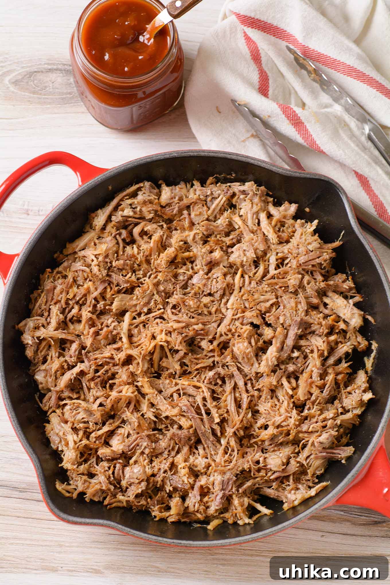 Fall-Apart Tender Oven Pulled Pork 4 An overhead view of pulled pork in a cast iron pan, showing the texture before any sauce is added.