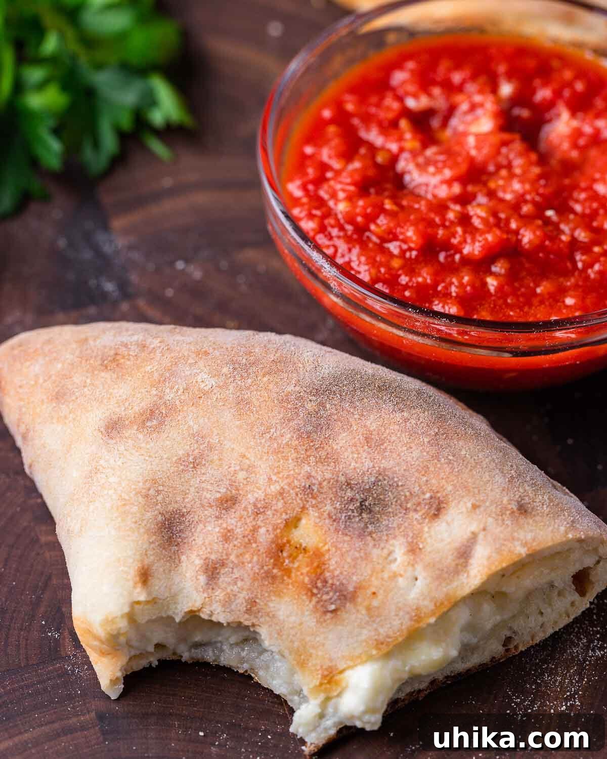 Half of a calzone with a bite taken out of it, revealing the rich, melted cheese filling.
