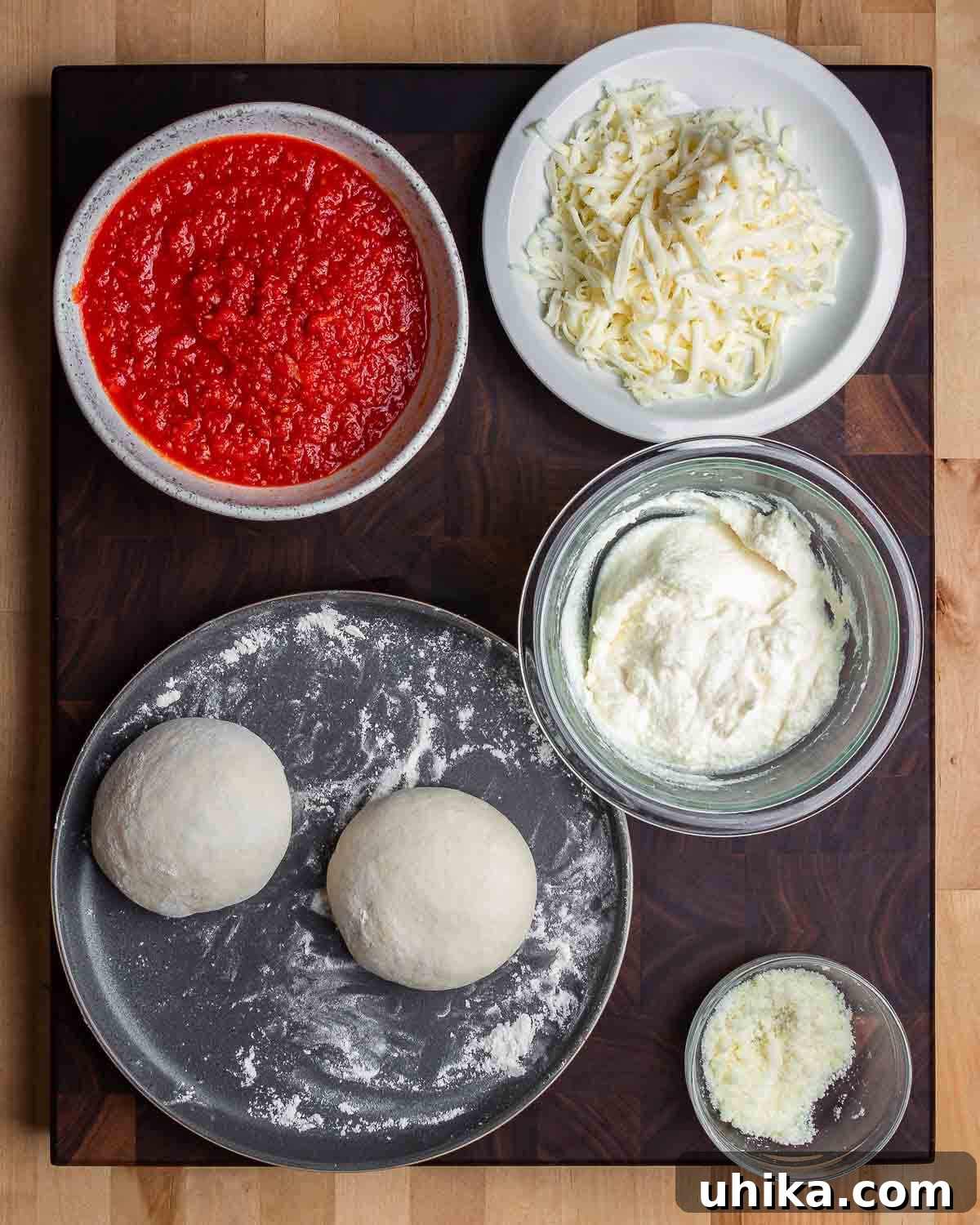 Golden Cheese Pocket 3 Ingredients shown: marinara sauce in a bowl, shredded mozzarella, fresh ricotta, two pizza dough balls, and grated Pecorino Romano cheese.