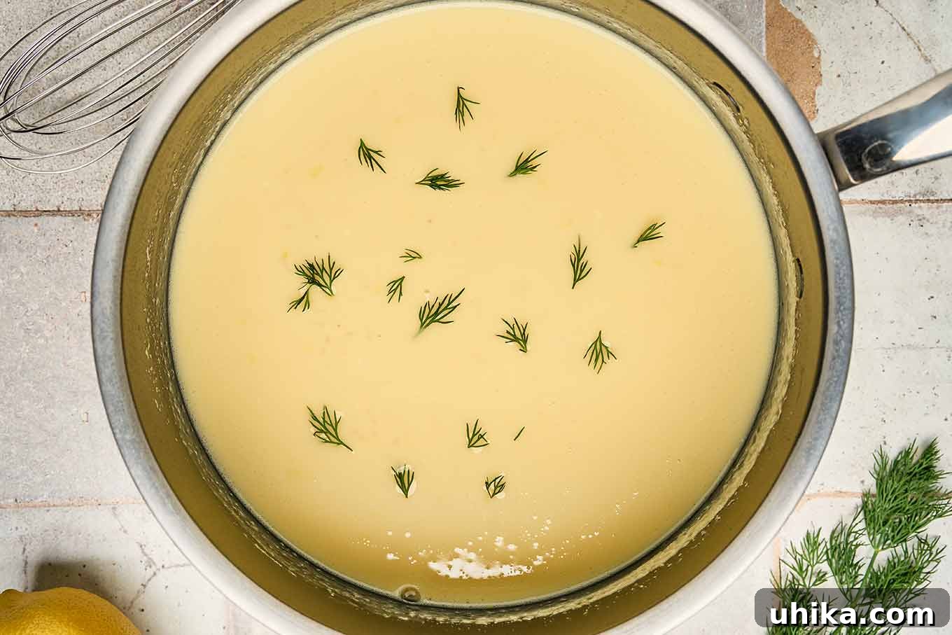 Golden Greek Avgolemono Soup 6 Traditional Greek egg and lemon soup, Avgolemono, gently thickening in a saucepan, garnished with fresh dill, showcasing its creamy texture during preparation.