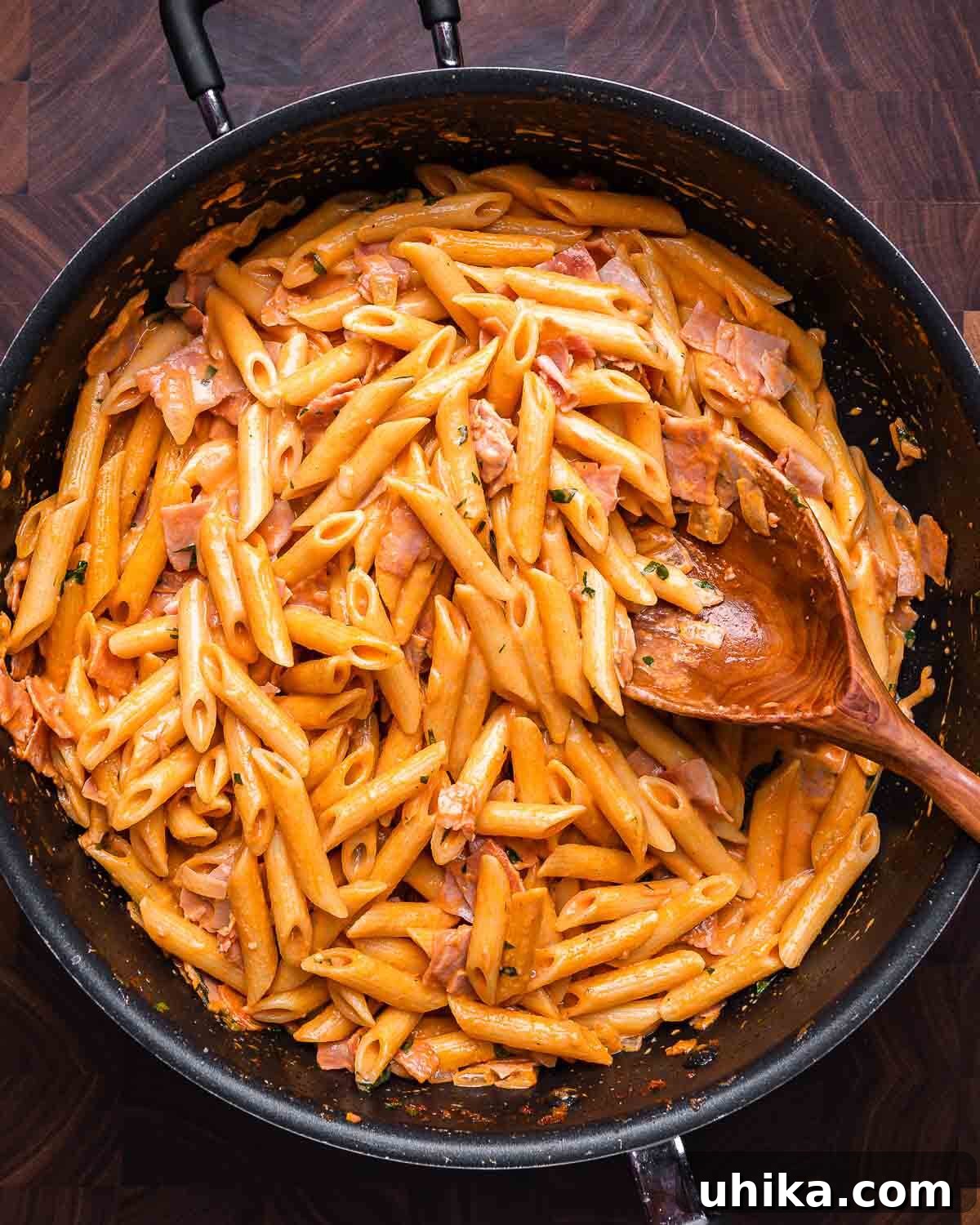 Overhead shot of a large pan filled with Penne al Baffo, showcasing its creamy pink sauce and ham pieces.