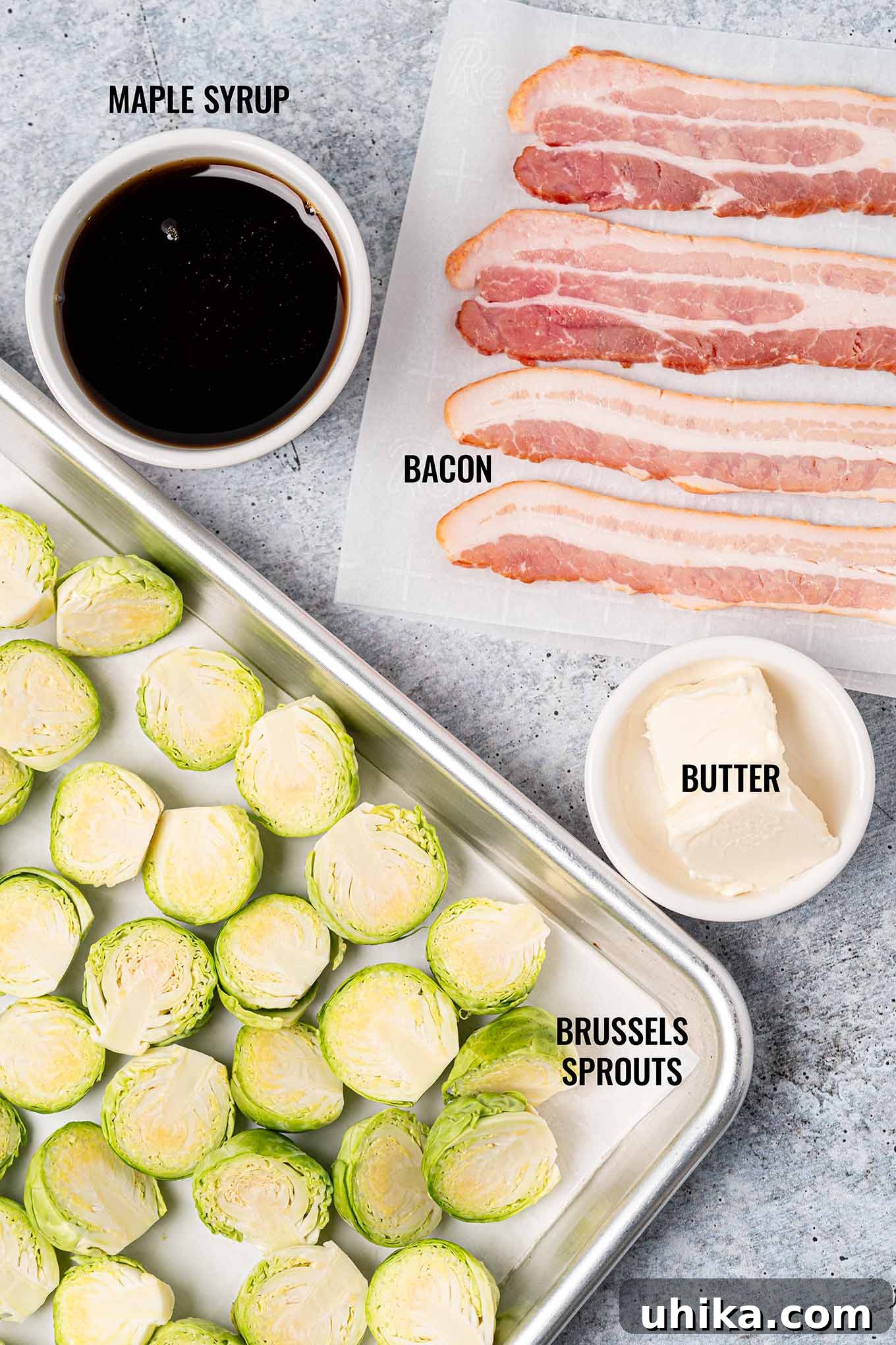 Sticky Maple Bacon Brussels Sprouts 3 A labeled, overhead view of the ingredients for maple glazed Brussels sprouts including bacon, maple syrup, butter, and fresh Brussels sprouts.